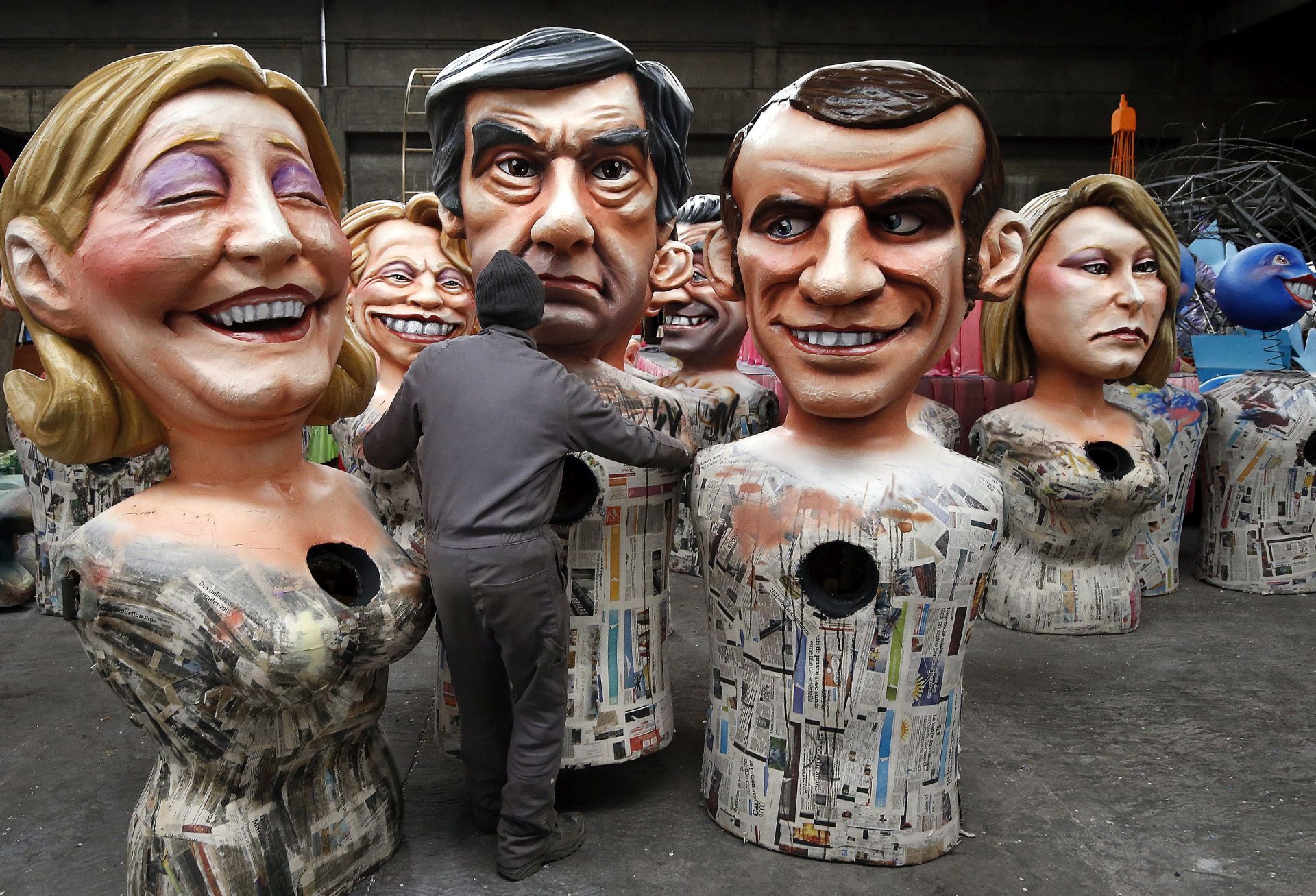 epa05754927 A worker gives final touches to the carnival characters depicting French presidential candidate and former Prime minister and right-wing candidate Francois Fillon (2-L) next to French presidential candidate, Leader of France's far-right Front National political party Marine Le Pen (L), presidential candidate and former French Economy Minister Emmanuel Macron (2-R) and French far-right political party National Front (FN) deputy, Marion Marechal-Le Pen (R)  during the 2017 Nice Carnival preparations, in Nice, France, 27 January 2017. The 131st annual Carnival of Nice will run from 11 to 25 February under the theme 'King of Energy'.  EPA/SEBASTIEN NOGIER