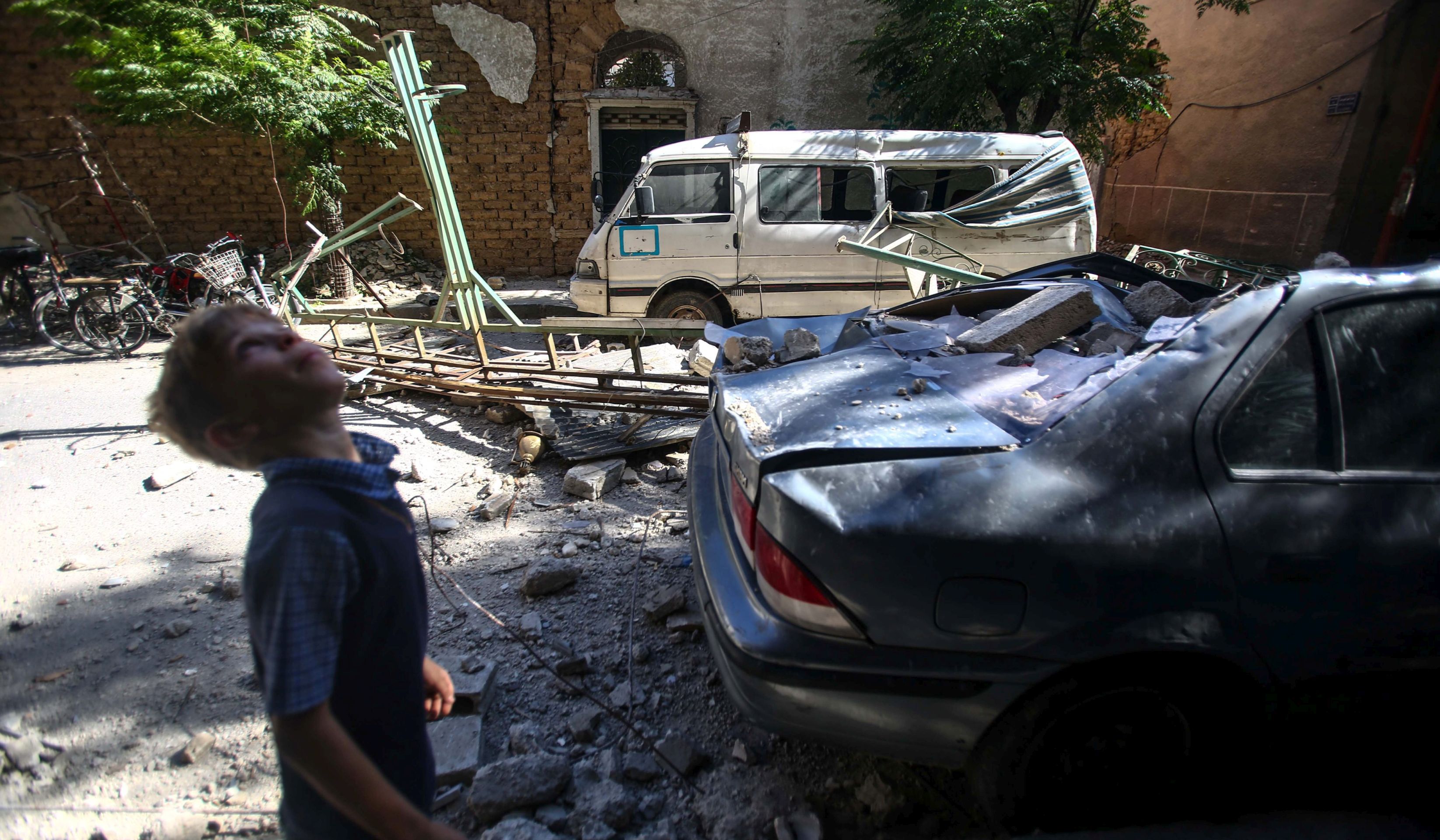 epa05435622 A Syrian child stands next to damaged vehicles and buildings in Douma, Syria, 21 July 2016. The death toll from airstrikes launched by warplanes in rebel-controlled areas in the outskirts of Damascus and the Syrian northern provinces of Idleb and Aleppo, has risen to 43, according to the Syrian Observatory for Human Rights (SOH) on 21 July. Thirteen people, including three children and three women, were killed in attacks by government aircraft in Douma, Hosh Nasri and al-Rihan in Eastern Ghouta, the main opposition stronghold near Damascus. For more than five years Syria has been the scene of a conflict that has killed more than 280,000 people, according to SOHR.  EPA/Mohammed Badra