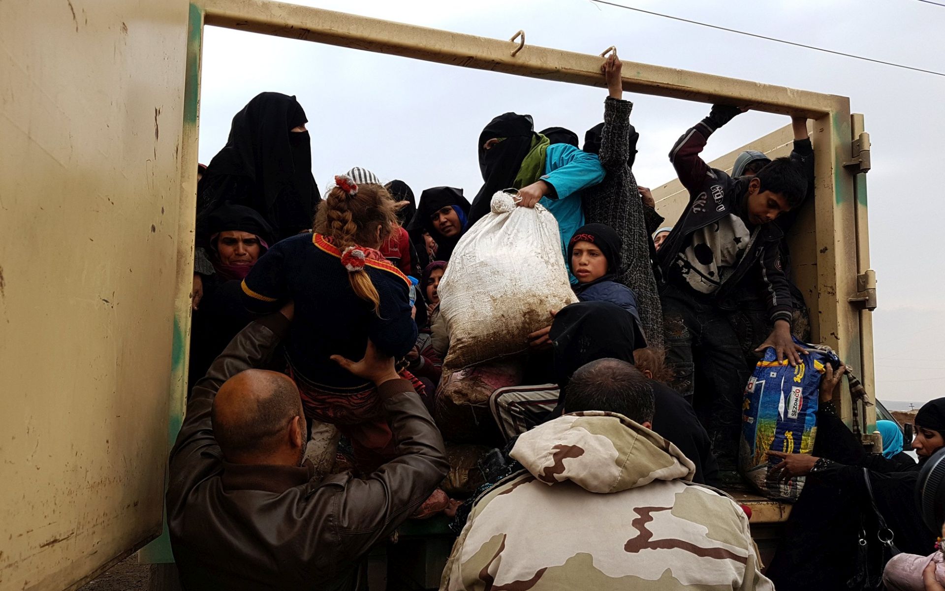 epa05828489 A picture made available on 04 March 2017, shows Iraqi displaced people who just fled from west of Mosul districts, arriving on board a military vehicle in Hamam Ali town, southern Mosul, northern Iraq, 03 March 2017. Around 30,000 people have fled Mosul since operations backed by a US-led coalition of states began as Iraqi forces advanced west of Mosul and took control over two districts, while they continue clearing roads and buildings in those areas from bombs, an Iraqi officer said.  EPA/BASEL RASOL
