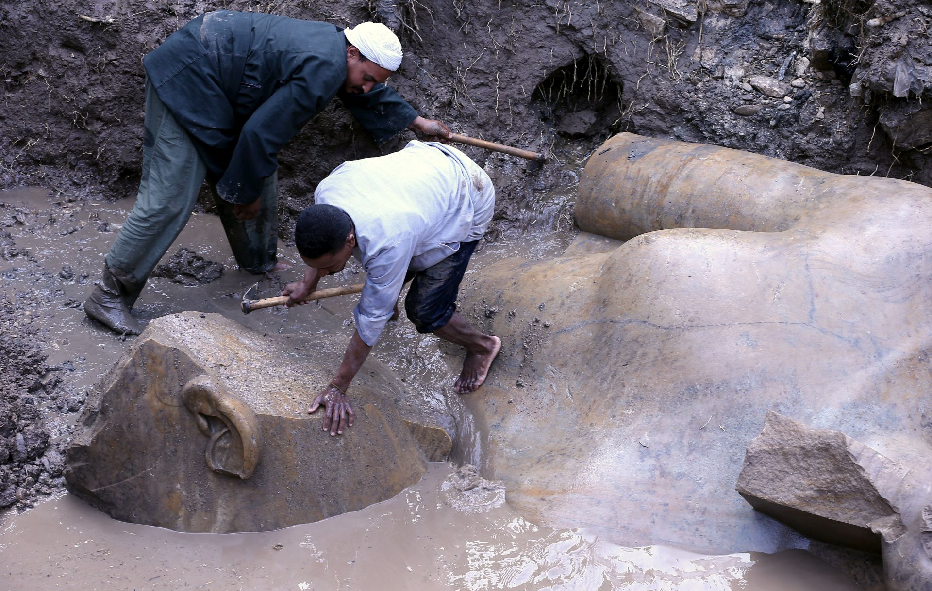 epa05838319 Egyptian workers prepare to lift parts of a statue for restoration after it was unearthed at Souq al-Khamis district, at al-Matareya area, Cairo, Egypt, 09 March 2017. According to the Ministry of Antiquities, a German-Egyptian archaeological mission found in parts two 19th dynasty royal statues in the vicinity of King Ramses II temple in ancient Heliopolis. The first is an 80cm tall bust of King Seti II carved in limestone, while the second is eight meters tall carved in quartzite. There were no engravings on the latter, however discovering it at the entrance of King Ramses II temple suggests that it could belong to him.  EPA/KHALED ELFIQI