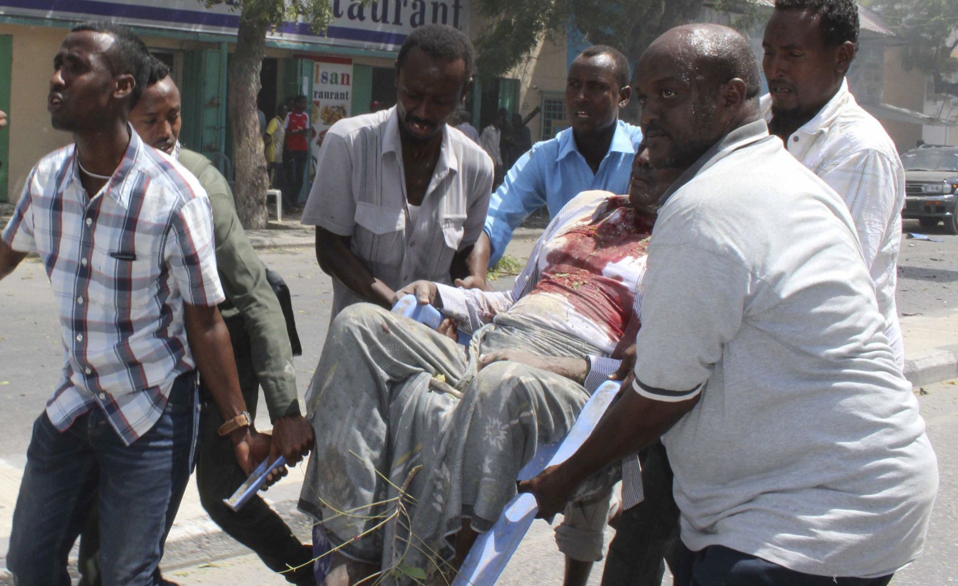 epa05845420 People carry an injured man on a plastic chair out of the scene of a car bomb explosion in Mogadishu, Somalia, 13 March 2017. At least 5 people have been killed when a car bomb exploded in the capital, according to an epa photographer on the site. No one has claimed responsibility for the attack but the country's Islamist militant group al-Shabab is often blamed for carrying out such attacks in Somalia.  EPA/SAID YUSUF WARSAME