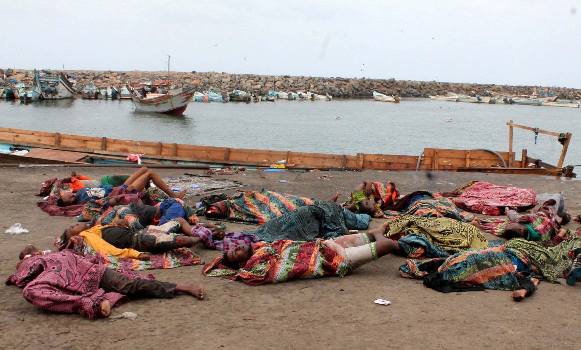 epa05854740 Bodies of Somali migrants, who were allegedly killed in a helicopter attack while traveling in a boat off the coast of Yemen, lay on the ground, in the western Yemeni city of Hodeida, 17 March 2017. According to media reports at least 42 Somali refugee died after their boat was attacked by a helicopter near Bab al-Mandeb Strait. The refugees carried UN refugee agency UNHCR documents.  EPA/ZAHIR MOHAMED ATTENTION EDITORS: PICTURE CONTAINS GRAPHIC CONTENT