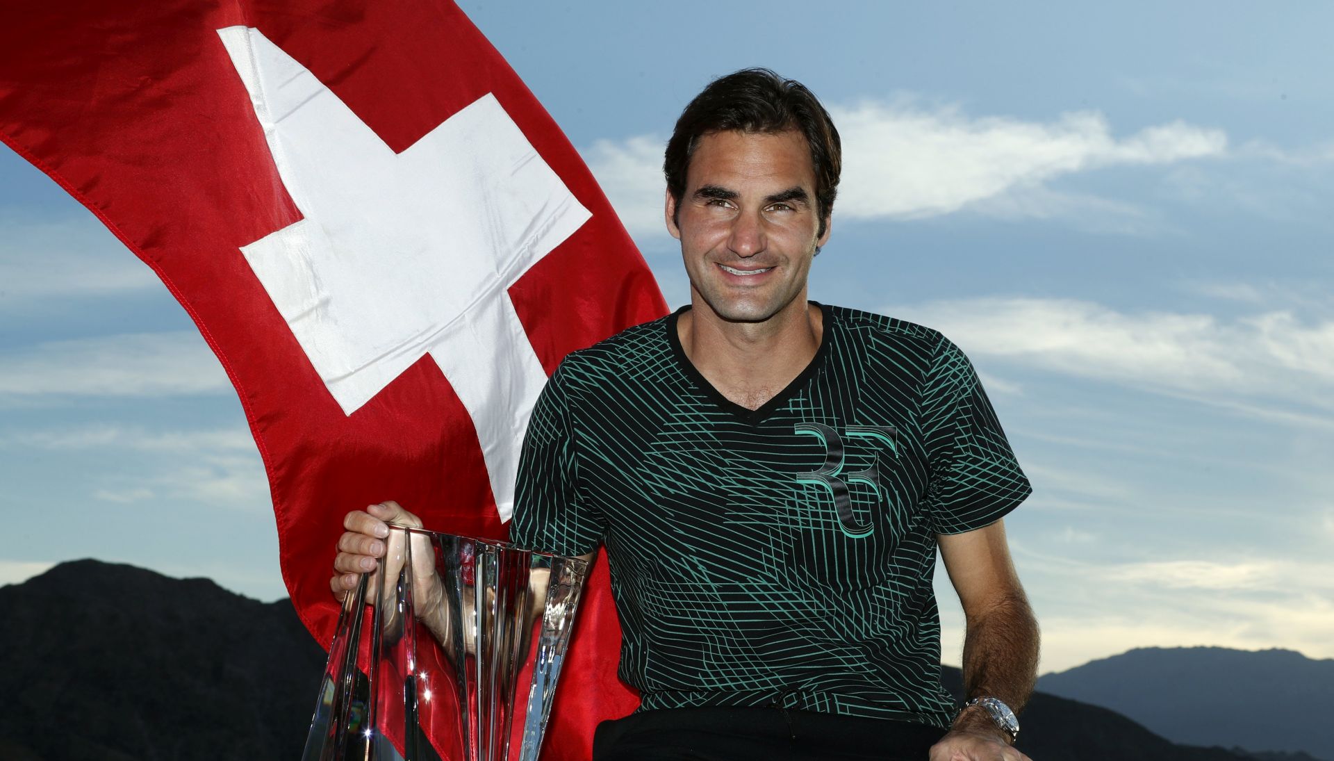 epa05859092 Roger Federer of Switzerland poses with the trophy and the Swiss national flag after defeating Stan Wawrinka of Switzerland in the men's final match at the 2017 BNP Paribas Open tennis tournament at the Indian Wells Tennis Garden in Indian Wells, California, USA, 19 March 2017.  EPA/PAUL BUCK