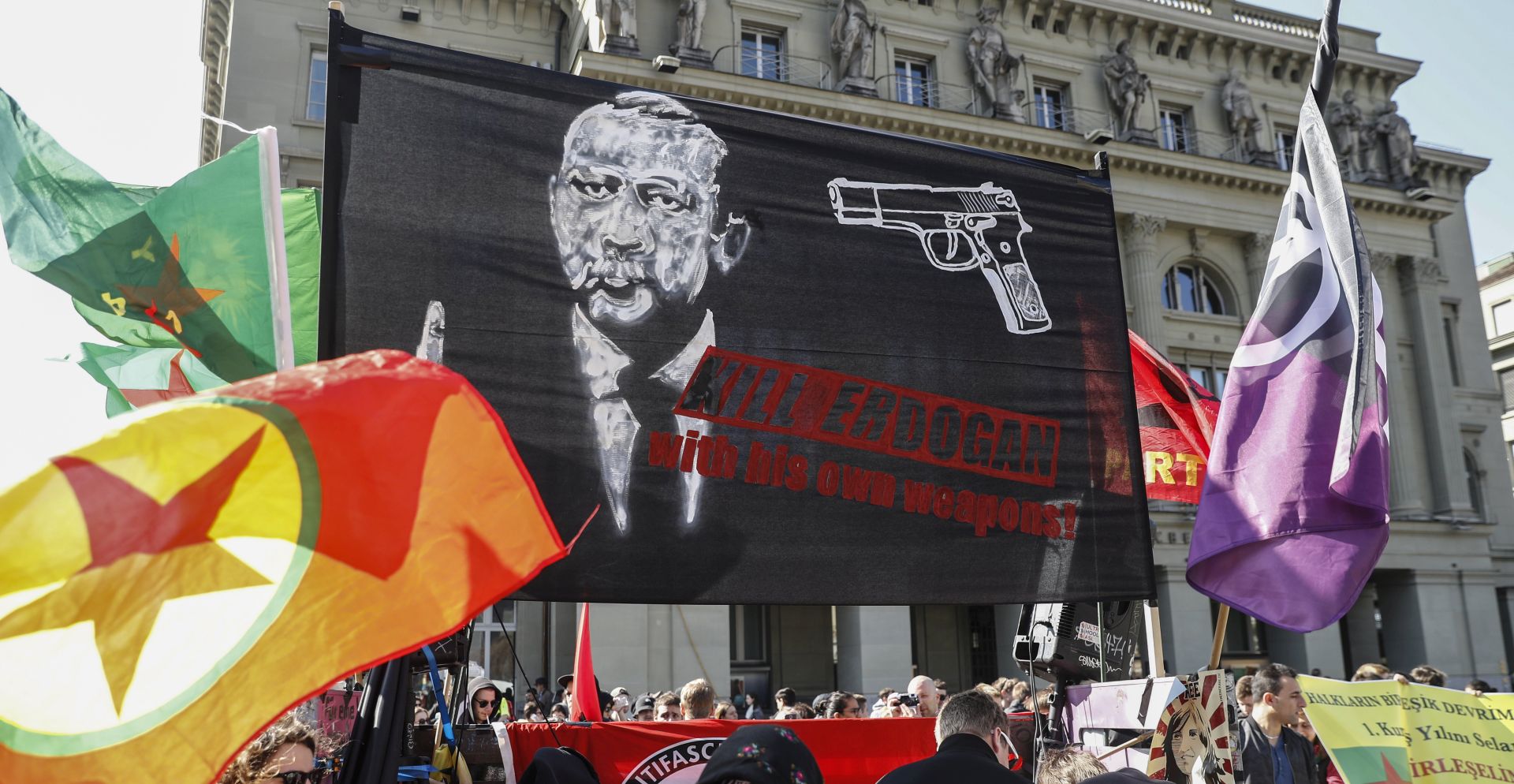 epa05870520 A banner reads; 'Kill Erdogan with his own weapons', as protesters march during a demonstration against the Turkish President Recep Tayyip Erdogan, in Bern, Switzerland, 25 March 2017.  EPA/PETER KLAUNZER
