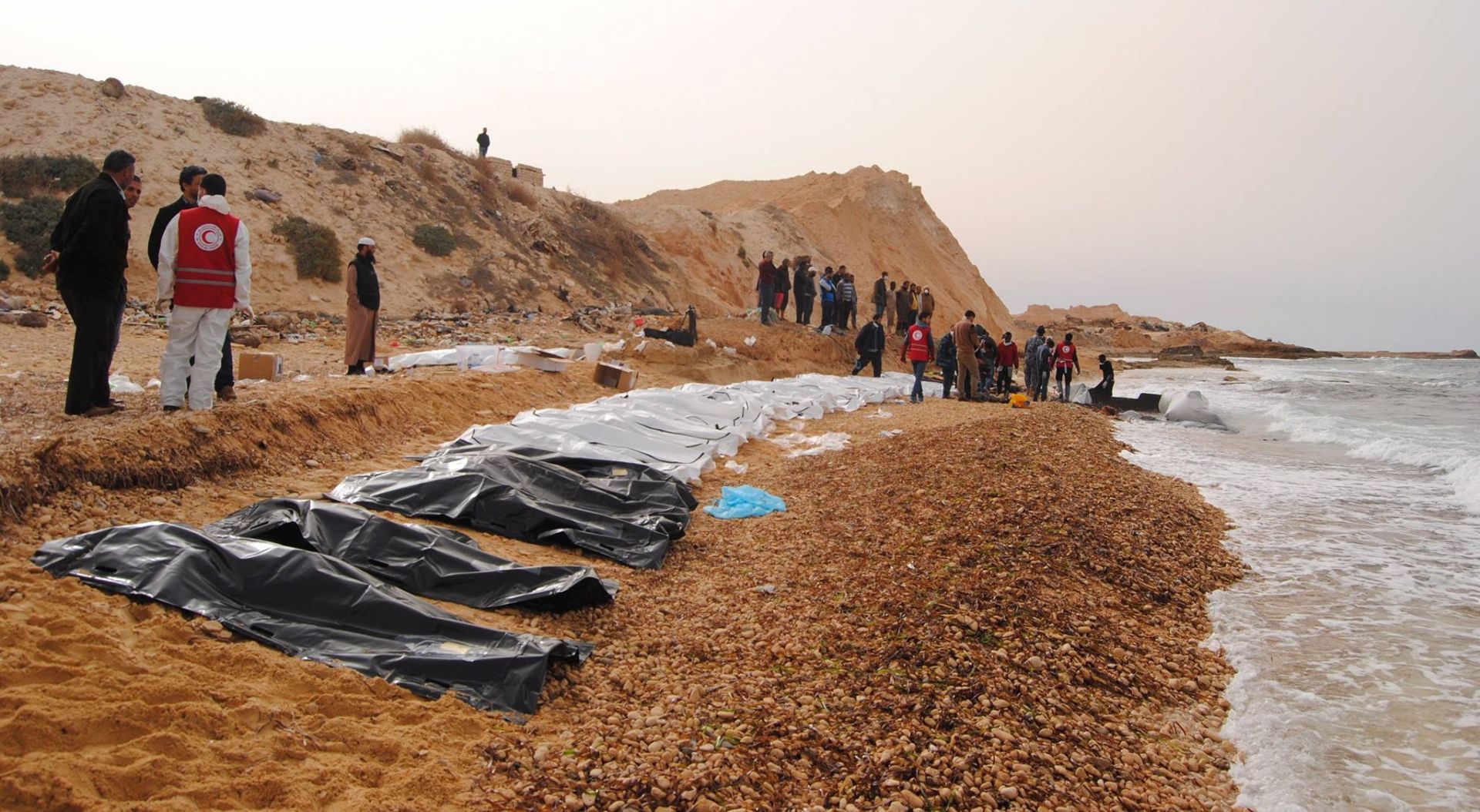 epa05806588 A handout photo made available by the Libyan Red Crescent shows volunteers of the Red Crescent recovering bodies washed ashore at the coast near Al Zawiya, Libya, 20 February 2017 (issued 21 February 2017). According to the Red Crescent, at least 74 bodies of suspected refugees trying to cross the Mediterranean Sea have been recovered by volunteers on 20 February.  EPA/LIBYAN RED CRESCENT HANDOUT BEST QUALITY AVAILABLE. HANDOUT EDITORIAL USE ONLY/NO SALES
