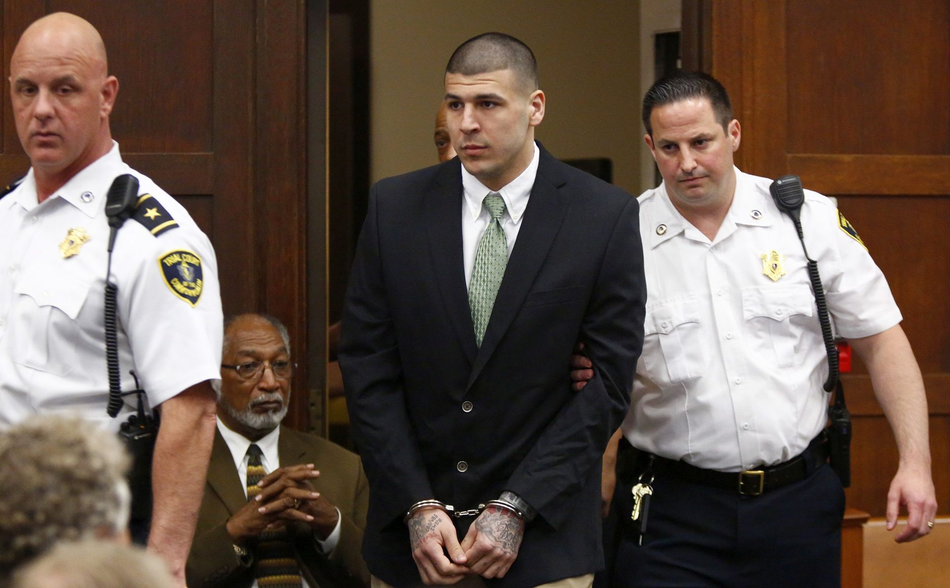 epa04230287 Former NFL American football player Aaron Hernandez (C) enters the courtroom to be arraigned on homicide charges at Suffolk Superior Court in Boston, Massachusetts, USA, 28 May 2014. Hernandez is accused of ambushing and shooting two men in 2012 after an altercation in a Boston nightclub. Hernandez already faces separate charges for the 2013 murder of semi-professional American football player Odin Lloyd.  EPA/Dominick Reuter / POOL