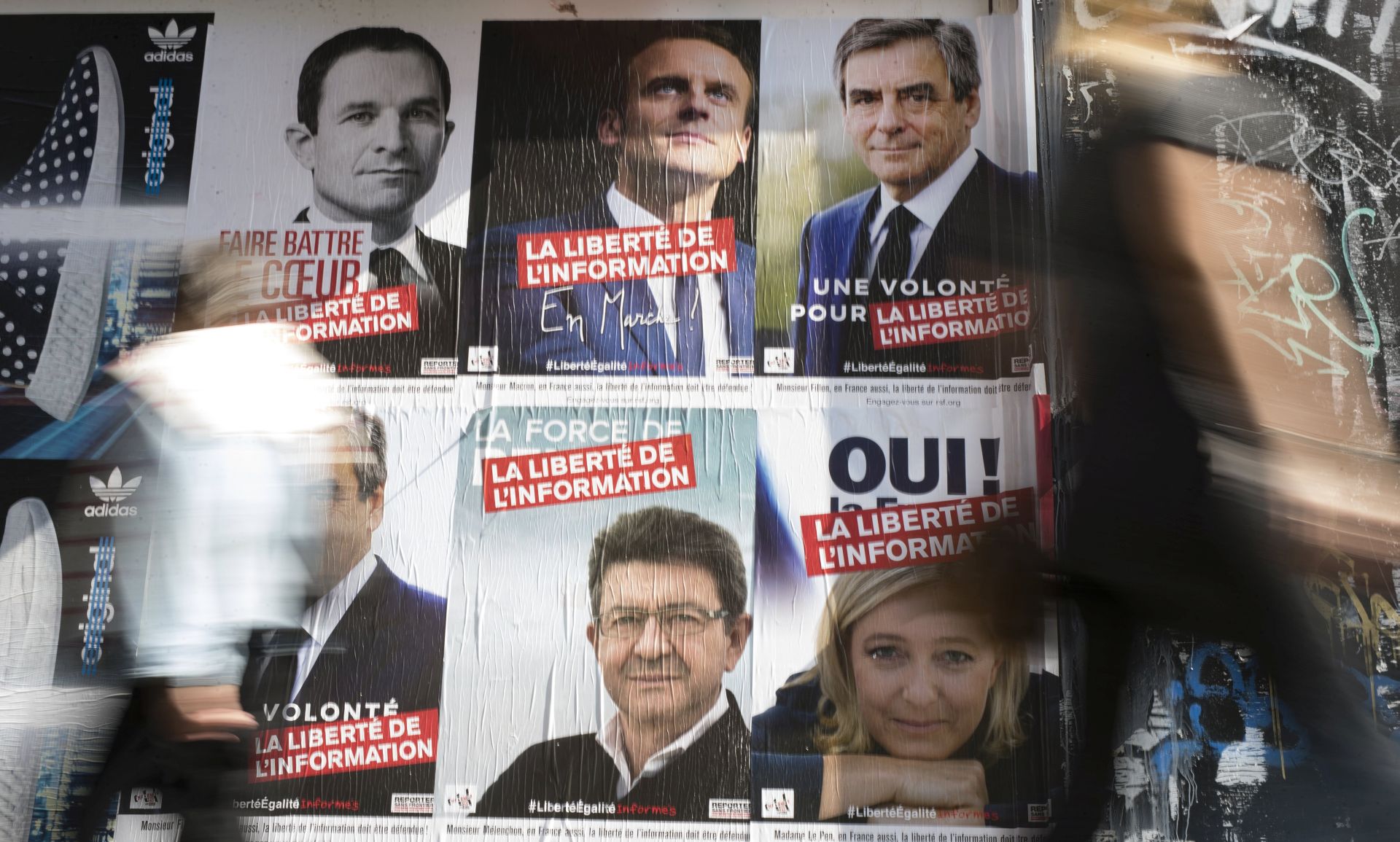 epa05896953 A pedestrian passes by posters by NGO group 'Reporters Without Borders' depicting six of the French presidential election candidates, including (clockewise from top left) Benoit Hamon, Emmanuel Macron, Francois Fillon, Marine Le Pen, Jen-Luc Melenchon,  in Paris, France, 08 April 2017. French presidential elections are planned for 23 April and 07 May 2017. The slogan over the candidates' portraits reads 'Liberty of Information'.  EPA/IAN LANGSDON