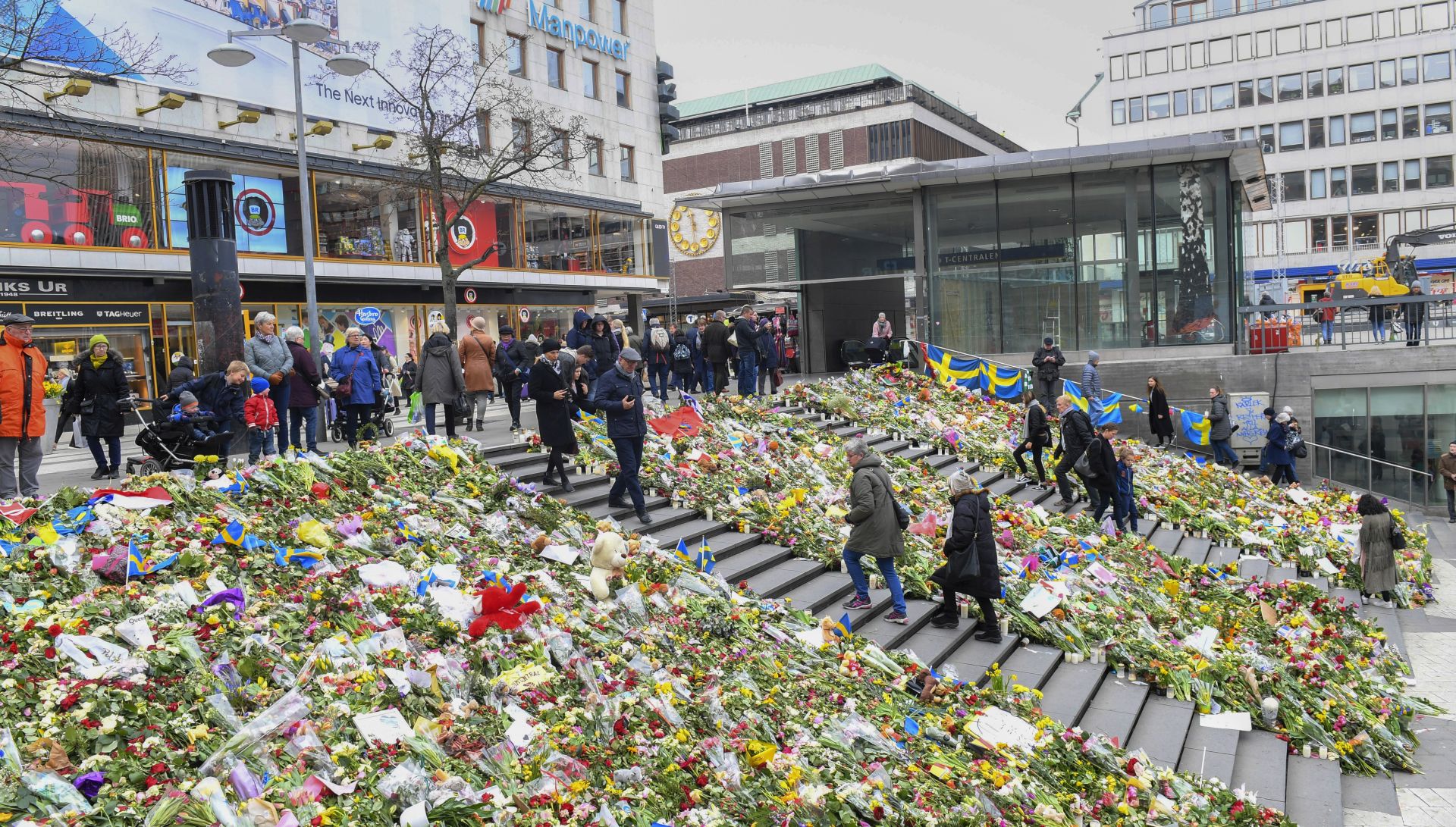 epa05904499 People walk between huge areas filled with flowers and greetings near the crime scene next to Ahlens department store in the pedestrian street Drottninggatan in central Stockholm, Sweden, 12 April 2017. A hijacked beer truck ploughed into pedestrians on Drottninggatan in the Swedish capital and crashed into a department store, killing four people, injuring 15 others late 07 April 2017.  EPA/FREDRIK SANDBERG  SWEDEN OUT