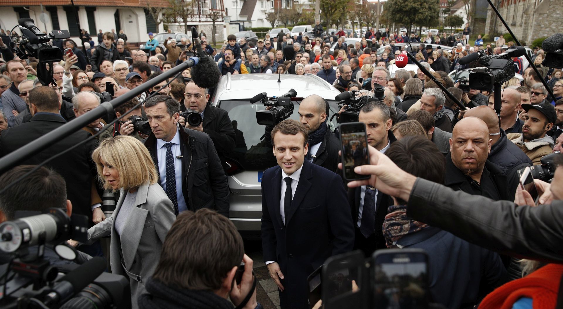 epa05922789 French presidential election candidate for the 'En Marche!' (Onwards!) political movement, Emmanuel Macron (C) and his wife Brigitte Trogneux (L) leave the Mayor house, the polling station, after casting their vote in the first round of the French presidential elections in Le Touquet-Paris-Plage, northern France, 23 April 2017. France will hold the second round of the presidential elections on 07 May 2017.  EPA/YOAN VALAT
