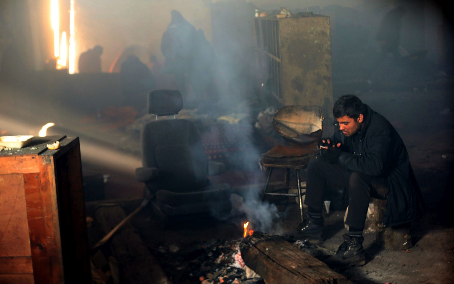 epa05761839 Migrants gather around a fire at the abandoned customs warehouse in Belgrade, Serbia, 30 January 2017. Migrants mostly from Afghanistan are struggling in the freezing temperatures that have hit Serbia in last couple of days. Low temperatures have caused traffic disruptions and cut off some rural parts of the country.  EPA/KOCA SULEJMANOVIC