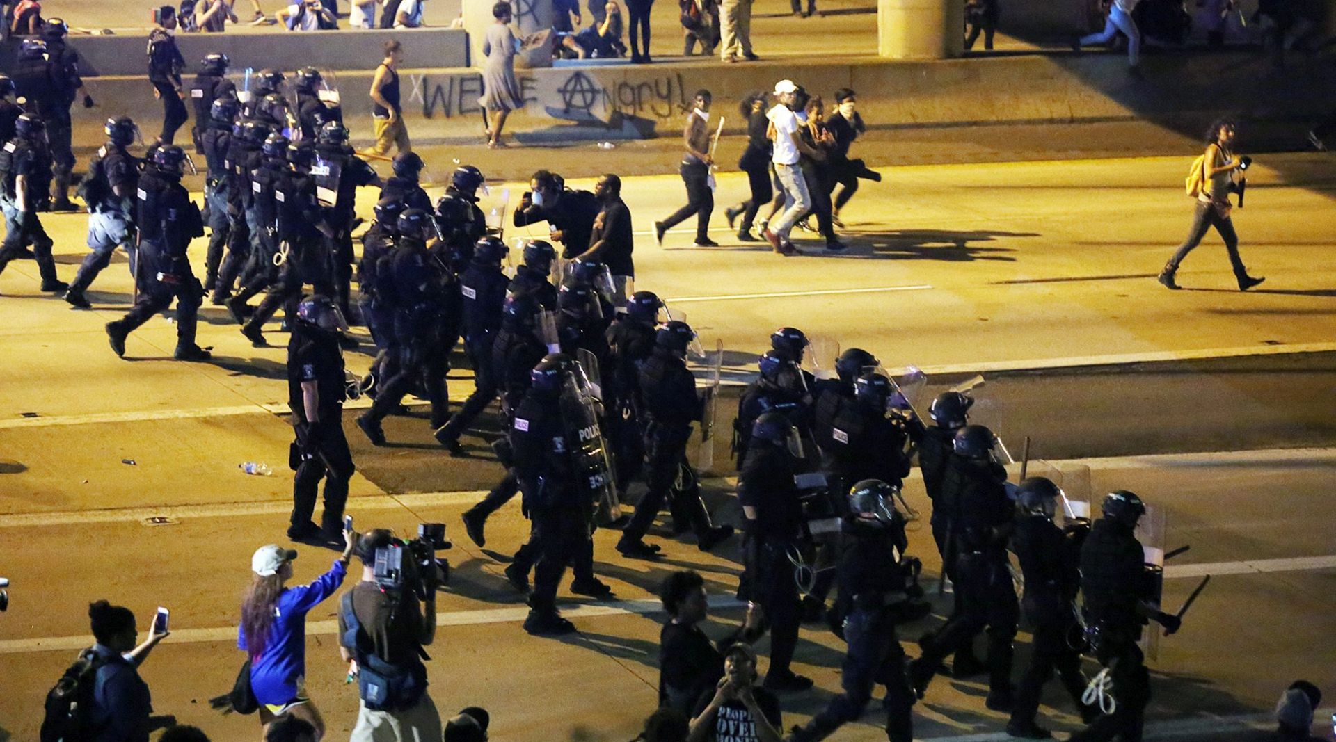 epa05552708 Riot police move to clear protestors from the I-277 highway after they briefly entered the road, in Charlotte, North Carolina, USA, 22 September 2016, after police officers shot and killed Keith Lamont Scott on 20 September. North Carolina governor Pat McCrory declared a state of emergency on 21 September after protesters took to the streets of Charlotte, North Carolina, for the second night in a row, demonstrating against the fatal shooting of African-American Keith Lamont Scott by police officers.  EPA/VEASEY CONWAY