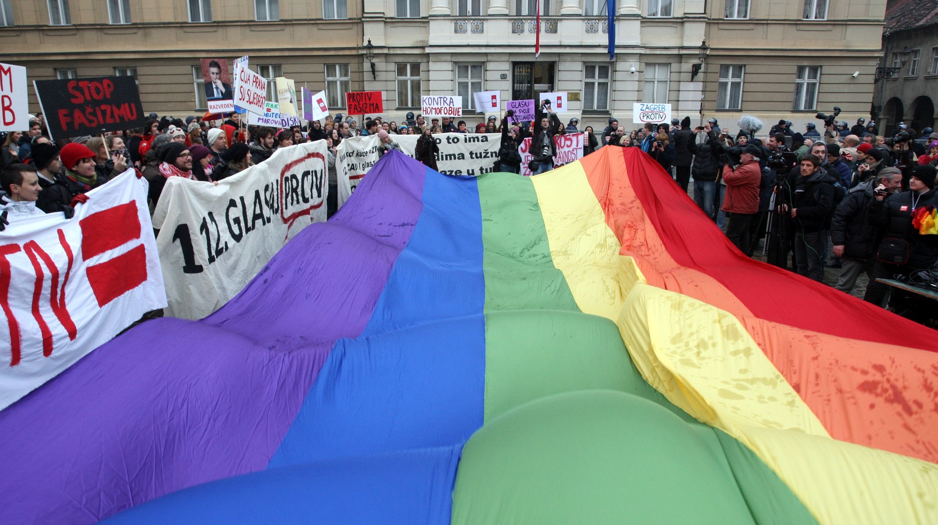 Zagreb, 30.11.2013 - Udruge Kontra, Ripet i enska mrea Hrvatske organiziraju mar "Glasam protiv" koji zapoèinje okupljanjem na Cvjetnom trgu u 12 sati, nakon èega æe se uputiti na Markov trg odakle æe graðane jo jedanput pozvati da na referendumu o ustavnoj definiciji braka glasaju protiv. Na slici povorka na Markovom trgu. Na slici velika zastava duginig boja na Trgu sv. Marka.
foto FaH/ Damir SENÈAR /ds