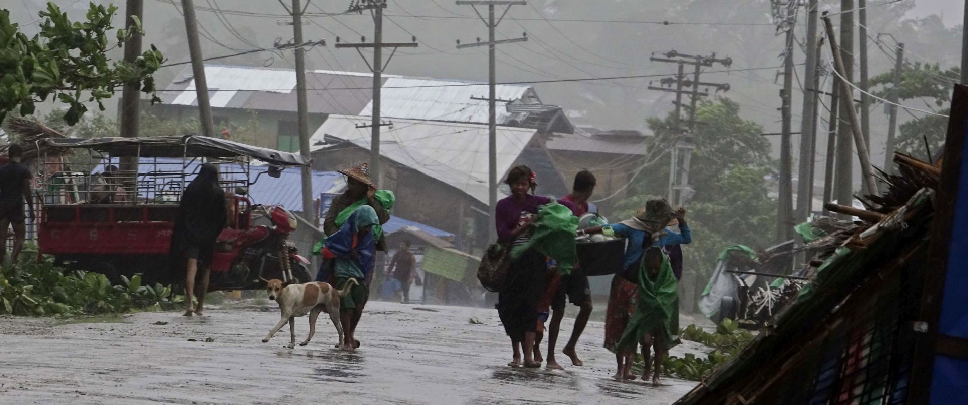 epa05998536 People carry their belongings as they walk near damaged houses in Sittwe, Rakhine State, western Myanmar, 30 May 2017. Some houses, trees and billboards in Sittwe have been damaged in the storm with no casualties reported, according to local sources. Tropical Cyclone Mora, which formed in the Bay of Bengal, is expected to hit Bangladesh, Northeast India and western Myanmar with strong winds and heavy rains.  EPA/NYUNT WIN