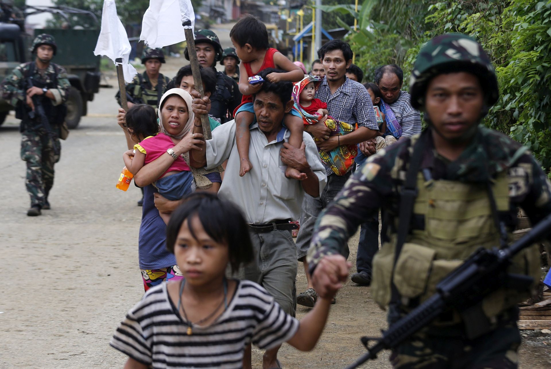 epa06000745 Trapped Filipino villagers are escorted by government troops during a rescue operation as fighting between Islamist militants and government forces continues in Marawi city, Mindanao island, southern Philippines, 31 May 2017. According to news reports, at least 104 people have been killed, including militants, security forces and civilians. The Philippines Army soldiers fighting in the area are enacting the martial law, declared by president Rodrigo Duterte for the island of Mindanao on the same day that the conflict emerged. The clashes began on 23 May when a military operation failed to capture Isnilon Hapilon, the leader of the extremist group Abu Sayyaf who was being safeguarded by members of the Maute Group, both groups have links to the so-called Islamic State (IS or ISIS, ISIL).  EPA/FRANCIS R. MALASIG