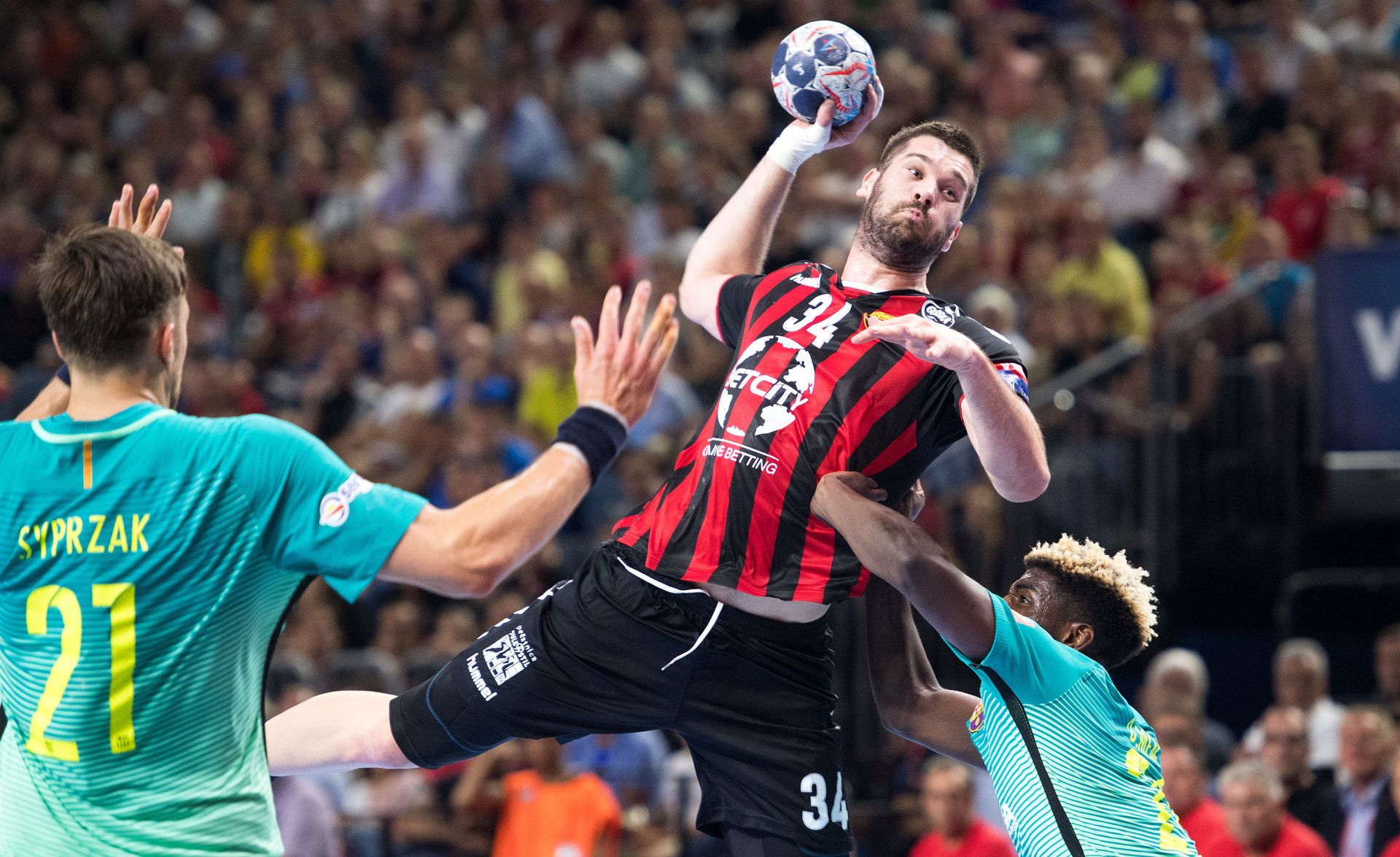 Barcelona's Dika Mem (R) tries to hinder Skopje's Vuko Borozan (C) from throwing the ball during the handball Champions League's Final Four semi-final match between Vardar Skopje and FC Barcelona in the Lanxess-Arena in Cologne, Germany, 03 June 2017. On the left side is Barcelona's Kamul Syprzak. Photo: Marius Becker/dpa