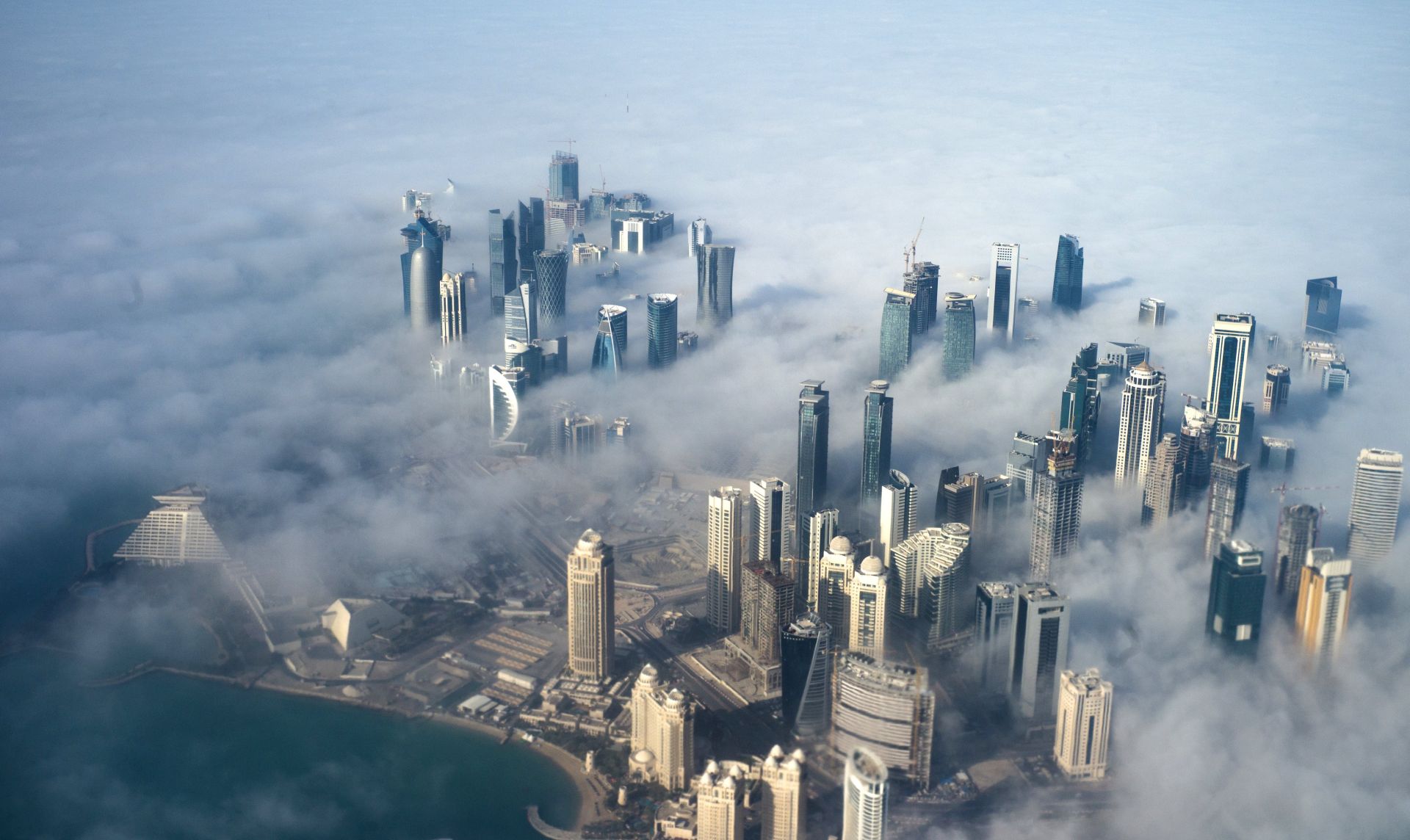 epa06011227 (FILE) - An aerial view of high-rise buildings emerging through fog covering the skyline of Doha, as the sun rises over the city, in Doha, Qatar, 15 February 2014 (reissued 05 June 2017). According to media reports, Egypt, Saudi Arabia, Bahrain and the United Arab Emirates cut off diplomatic ties with Qatar on 05 June 2017, accusing Qatar of supporting terrorism.  EPA/YOAN VALAT