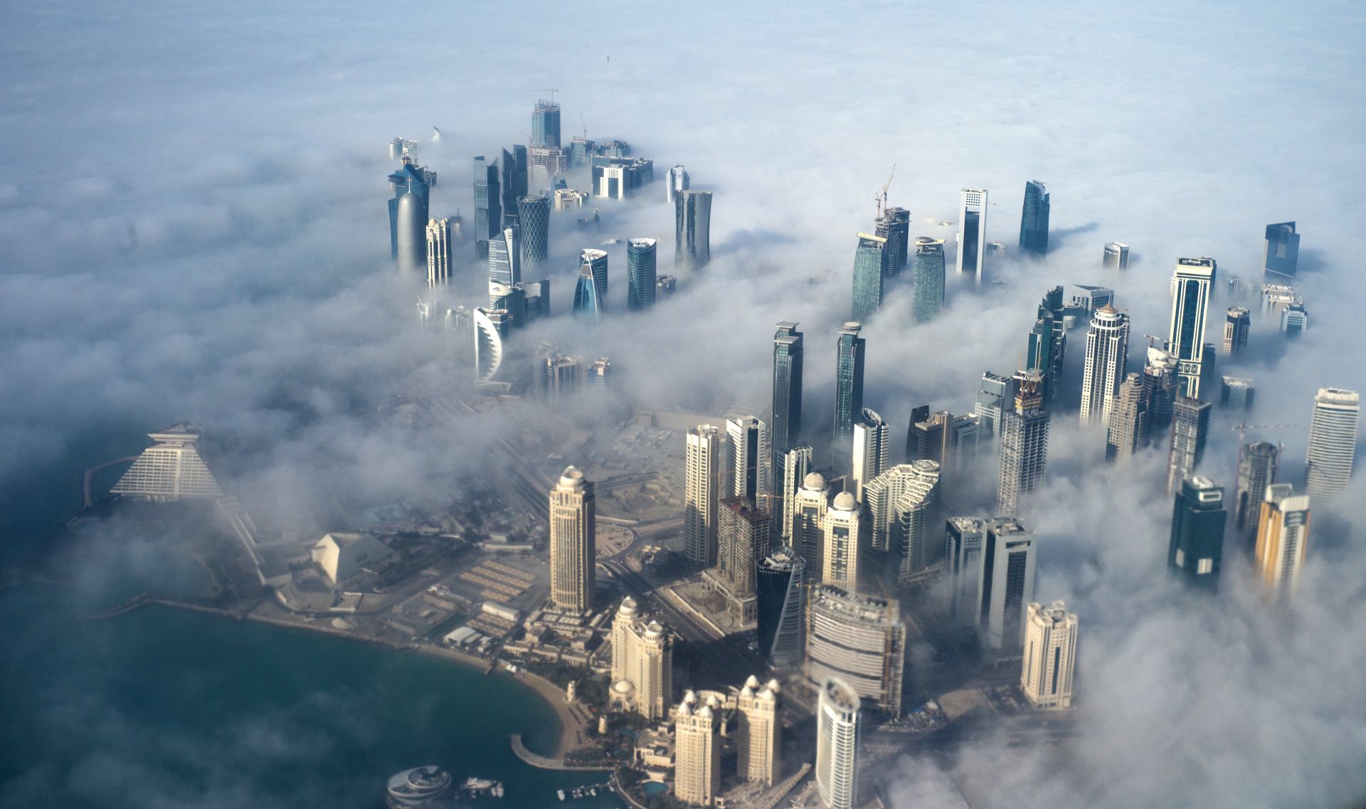 epa06011227 (FILE) - An aerial view of high-rise buildings emerging through fog covering the skyline of Doha, as the sun rises over the city, in Doha, Qatar, 15 February 2014 (reissued 05 June 2017). According to media reports, Egypt, Saudi Arabia, Bahrain and the United Arab Emirates cut off diplomatic ties with Qatar on 05 June 2017, accusing Qatar of supporting terrorism.  EPA/YOAN VALAT