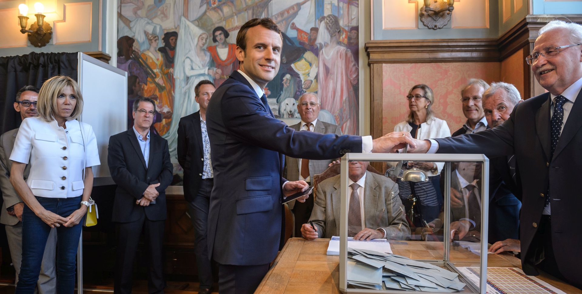epa06022260 French President Emmanuel Macron (C) with his wife Brigitte Trogneux (L) cast their ballot at their polling station in the first round of the French legislatives elections in Le Touquet, northern France, 11 June 2017. France holds the first round of parliamentary elections on 11 June 2017, just under two months after Macron took office as French President.  EPA/CHRISTOPHE PETIT TESSON / POOL