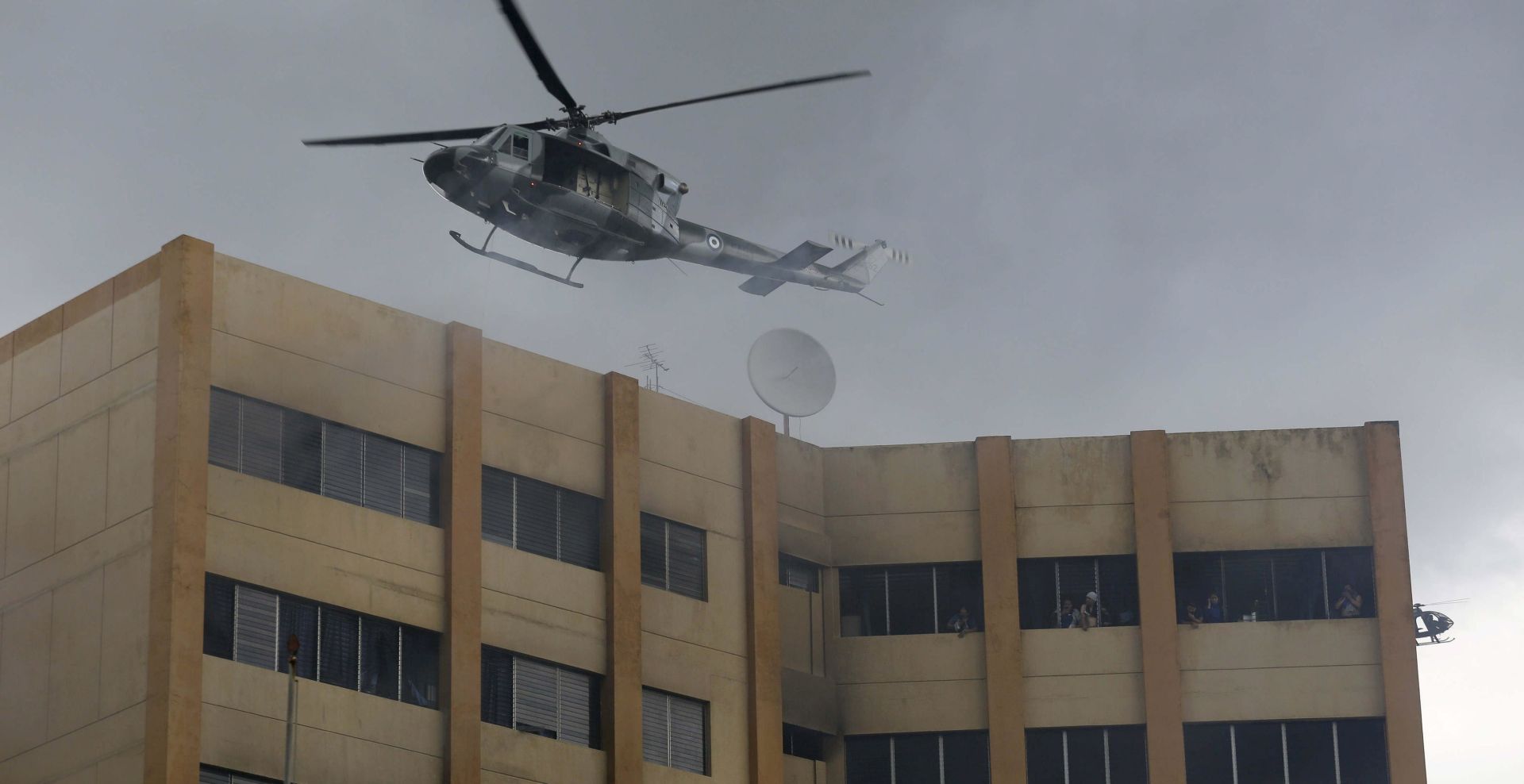 epa06074649 A helicopter of the Salvadoran Armed Forces works on the extinction of a fire in the headquarters of the Ministry of Finance in San Salvador, El Salvador, 07 July 2017. At least one person died in a major fire affecting the headquarters of the Ministry of Finance, said Human Rights Ombudsman Raquel Caballero. A number of people was injured in the incident, media reported.  EPA/RODRIGO SURA