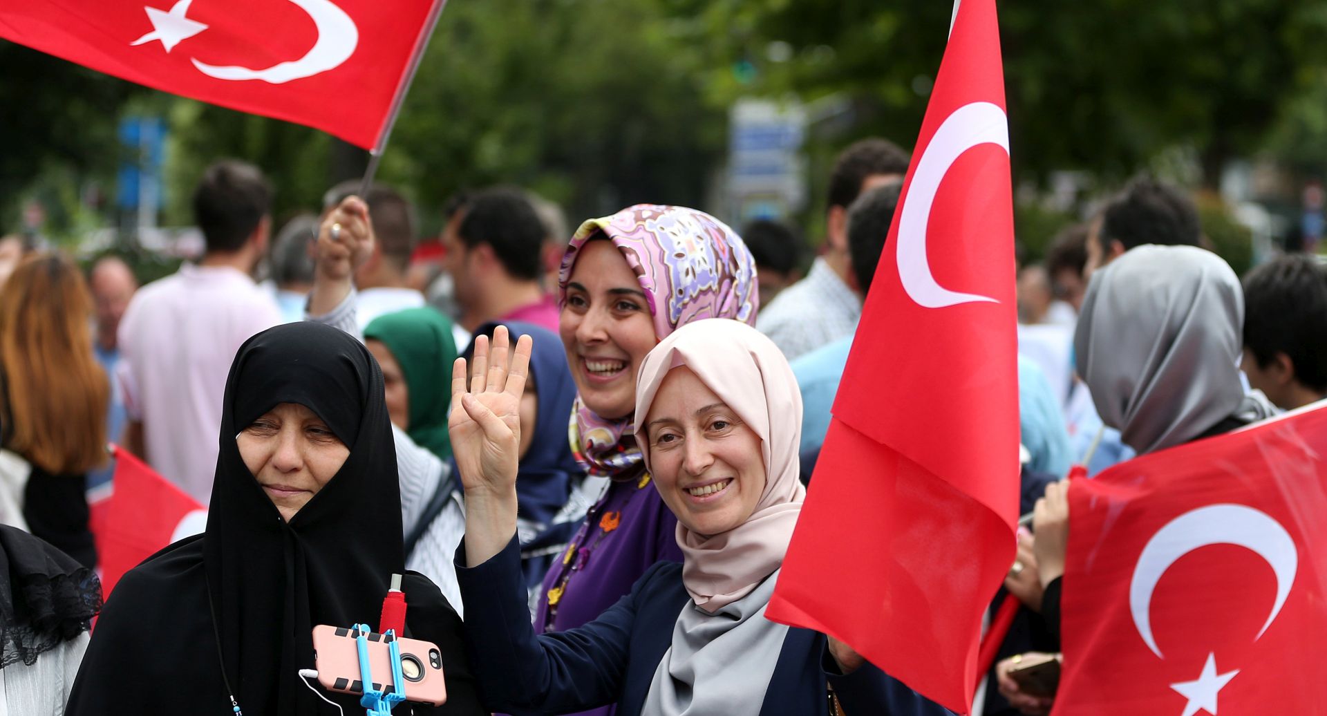 epa06087043 Women hold Turkish flag and sign of Rabia during a rally of first anniversary of the failed coup attempt in Istanbul, Turkey, 14 July 2017. The 15 July 2017 event marks the first anniversary of the failed coup attempt which led to some 50 thousand workers being dismissed, some eight thousand people arrested, and scores of news outlets shut down by the government. Turkish President Recep Tayyip Erdogan blamed US-based Turkish cleric Fetullah Gulen and his movement for masterminding the failed coup and Turkey remains under a state of emergency as a result.  EPA/ERDEM SAHIN