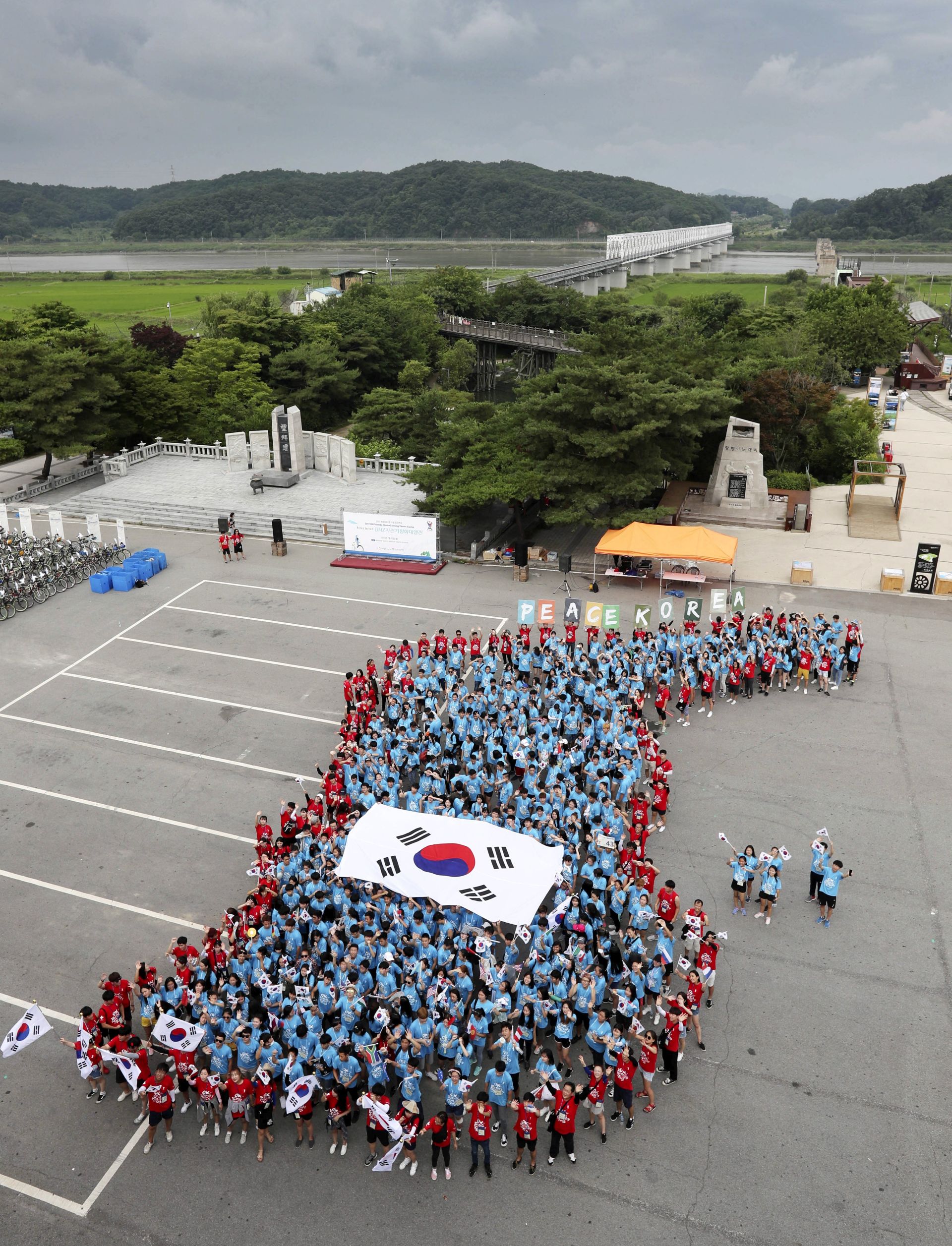 epa06092195 People stand to form a map of the Korean Peninsula before beginning a cycling ride on a road that runs along the Demilitarized Zone (DMZ) separating the two Koreas at the Imjingak Pavilion in Paju, north of Seoul, South Korea, 17 July 2017. The event, organized by the Overseas Koreans Foundation, is aimed at promoting inter-Korean peace. South Korean defense ministry proposed to North Korea on 17 July, that inter-Korean military talks be held on 21 July, on reducing tensions along the border.  EPA/YONHAP SOUTH KOREA OUT