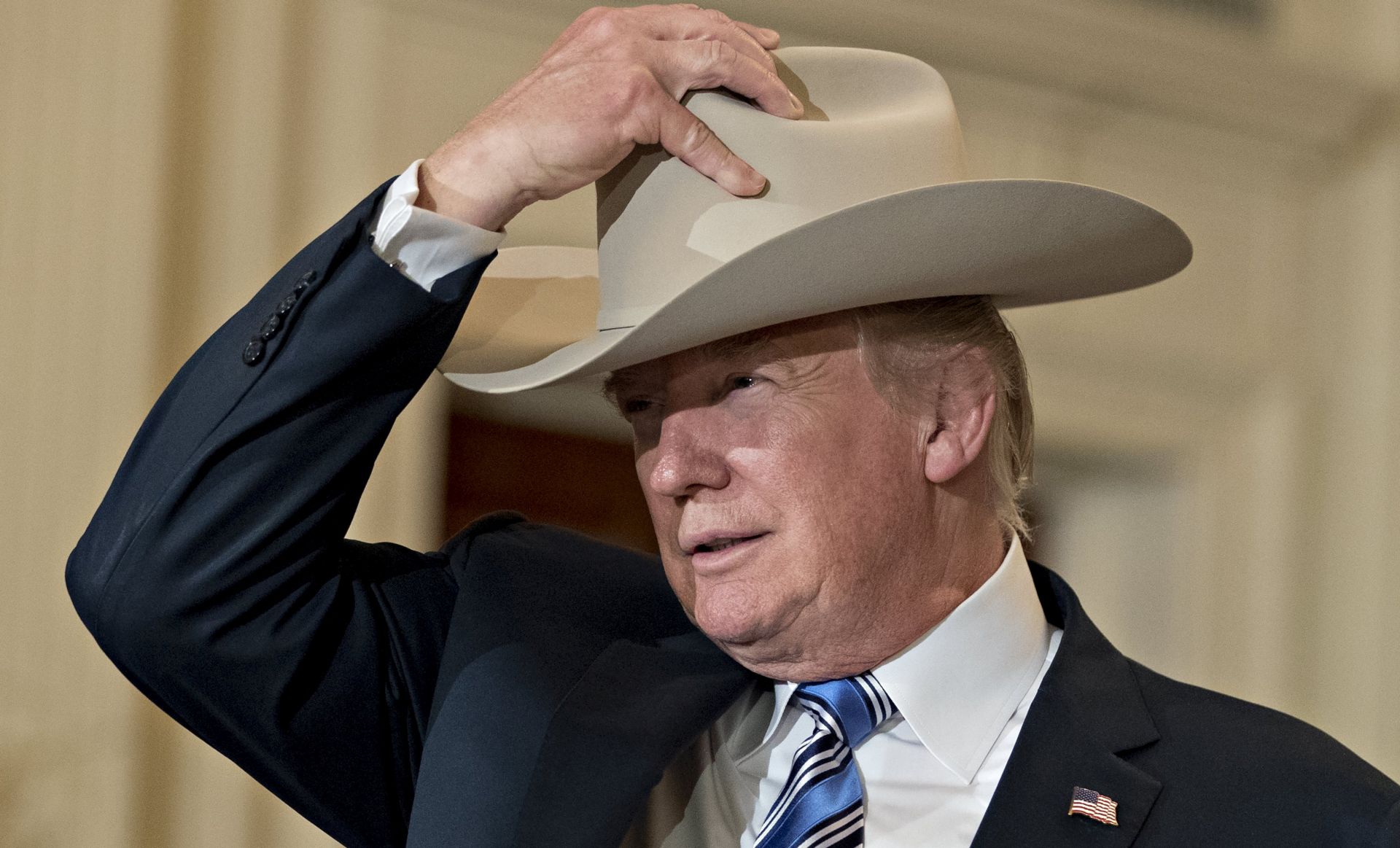epa06093576 US President Donald J. Trump puts on a Stetson cowboy hat while participating in a Made in America event with companies from 50 states featuring their products in the East Room of the White House in Washington, DC, USA, 17 July 2017. US President Donald J. Trump participated at the White House in a showcase of products 'Made in America', which featured 50 products from the 50 states of the nation. Trump signed a presidential proclamation in the East Room making 17 July 'Made in America' Day and this week, 'Made in America' week.  EPA/Andrew Harrer / POOL