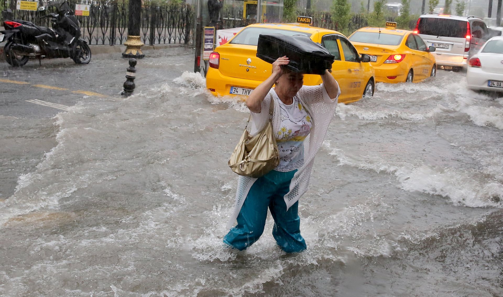 epa06094110 A Pedestrian struggles to cross a flooded street after torrential rain in Istanbul, Turkey, 18 July 2017. Heavy rain caused extensive flooding of roads and stations in Istanbul.  EPA/STRINGER