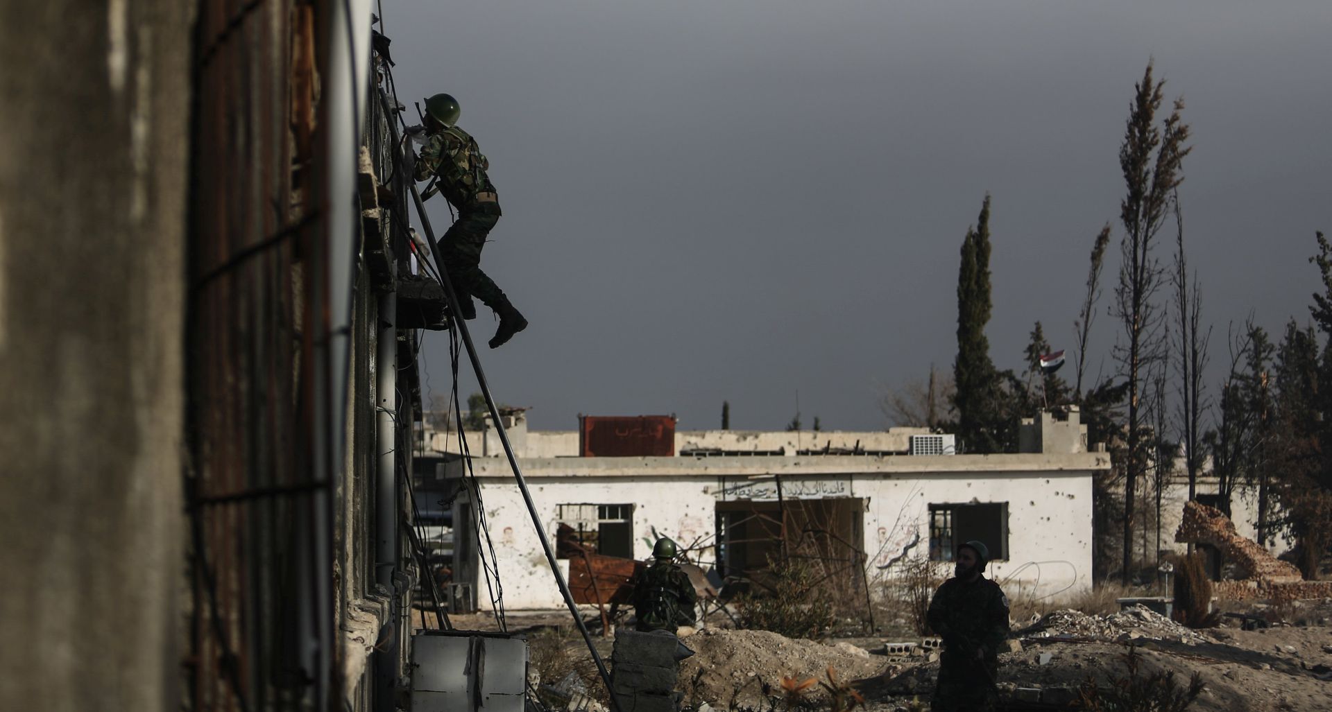 epa06097819 (14/25) A cadet climbs up a building with Hezbollah flag on it as others look during a training drill to infiltrate and capture a make-believe Hezbollah building, in Jaysh al-Islam Military Academy, in an undisclosed location, rebel-held Eastern Ghouta, outskirts of Damascus, Syria, 09 January 2017. In February 2016, Jaysh al-Islam announced the establishing of a Military Academy, after efforts from its former leader Zahran Alloush who died in December 2015. The academy is conducted in cooperation with the Military Council for Damascus and its Suburbs. The goals of the academy is to graduate fighters with thorough background in fighting tactics, and to enlist its graduates in the newly formed Unified Syrian National Army called for by various rebel groups.  EPA/MOHAMMED BADRA ATTENTION: For the full PHOTO ESSAY text please see Advisory Notice epa06097805