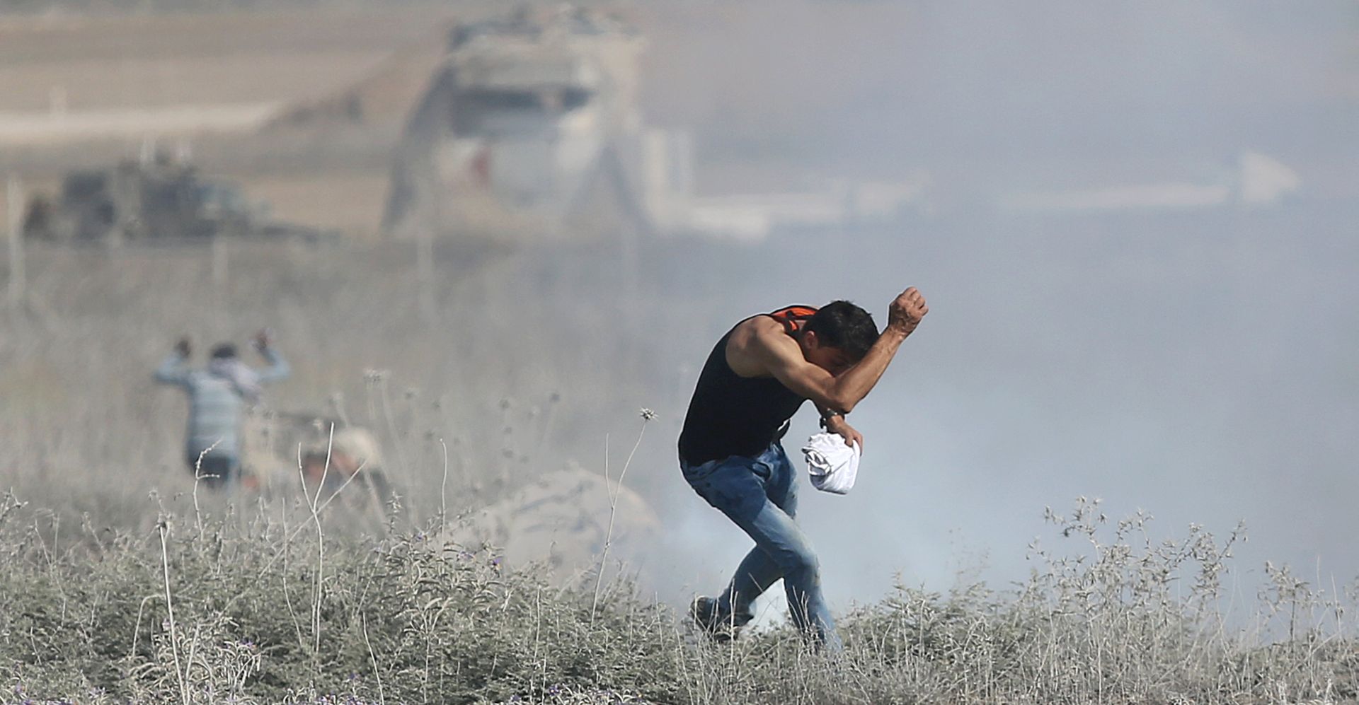epa06102647 A Palestinian protester ducks during clashes with Israeli troops near the border with Israel that followed a protest against the security measures at the Al-Aqsa mosque after the Muslim Friday prayer, in the eastern Gaza Strip, 21 July 2017. Israel authorities earlier had installed metal detectors at the entrance to the Al-Aqsa compound after a shooting attack carried out by Israeli Arabs on 14 July against Israeli police during which two Israeli policemen and three attackers were killed. The mufti of Jerusalem had called Palestinian Muslims not to go through the electronic gates and to reject all procedures that change the historic situation of the mosque. The measures reportedly were prohibiting Friday prayers for Muslims at the mosque for the first time in 48 years.  EPA/MOHAMMED SABER