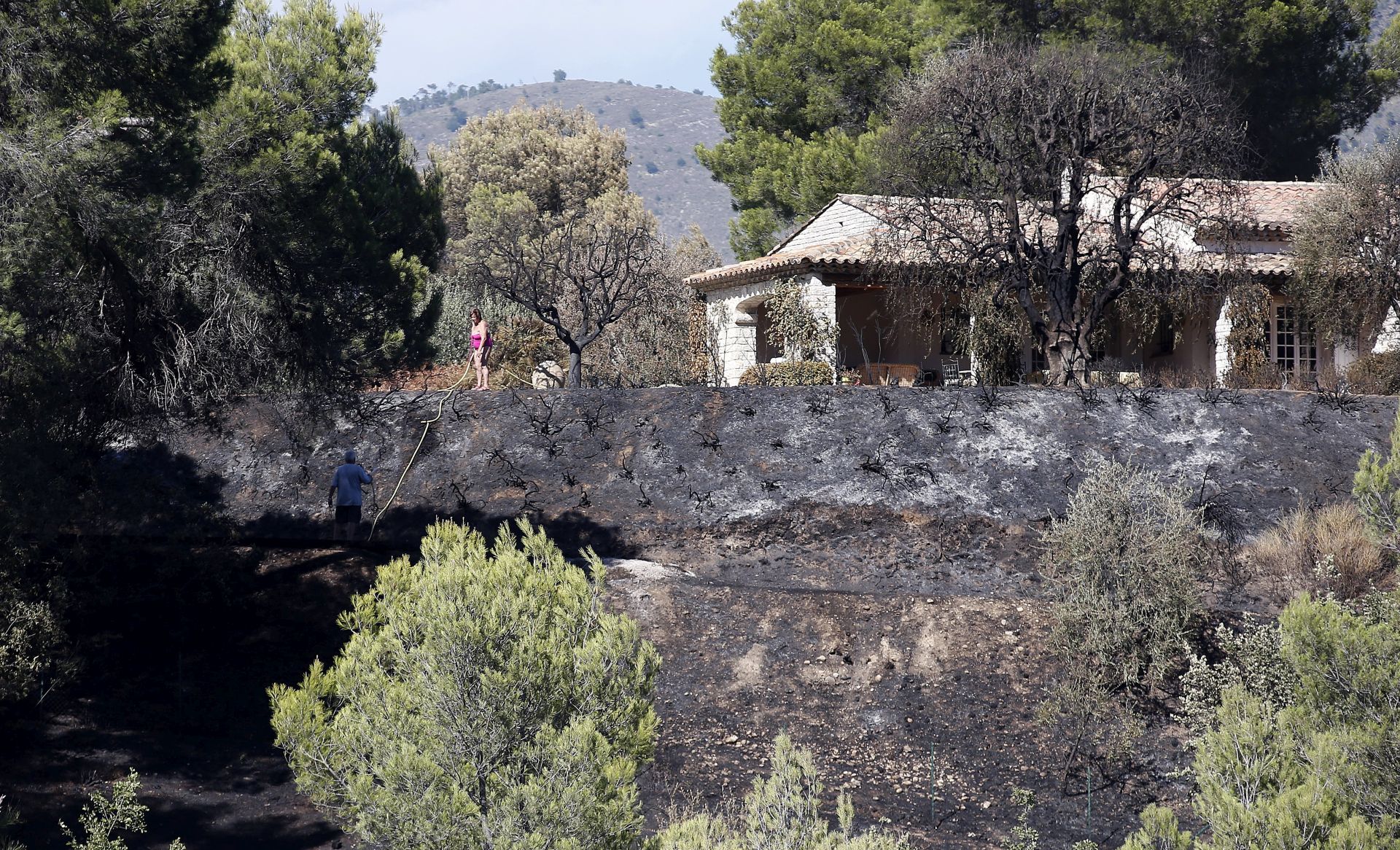 epa06108970 Local resident view the damages after a forest fire in Carros near Nice, southern France, 25 July 2017.  EPA/SEBASTIEN NOGIER