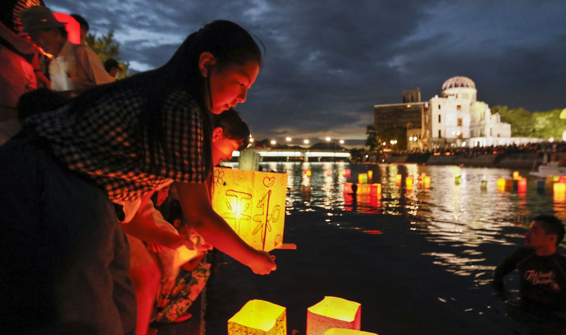 epa06128341 A girl floats a paper lantern to comfort souls of victims of the 06 August 1945 atomic bombing, at Hiroshima Peace Memorial Park in Hiroshima, western Japan, 06 August 2017. Hiroshima marked the 72nd anniversary of the atomic bombing on 06 August 2017. The Atomic Bomb Dome is seen in the rear.  EPA/KIMIMASA MAYAMA
