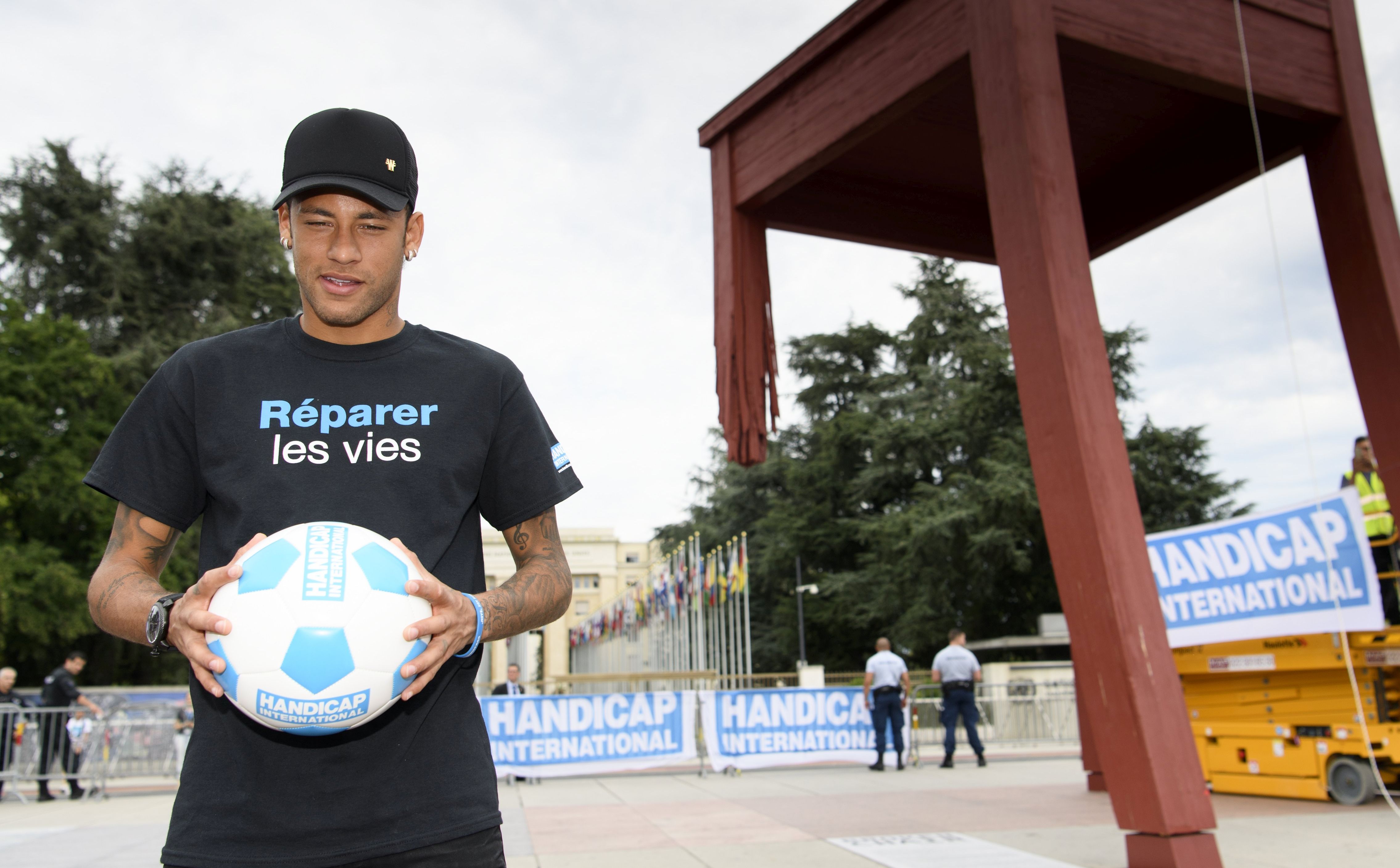 epa06145685 Paris Saint Germain's (PSG) Brazilian player Neymar poses with a ball in front of the "Broken Chair" sculpture, a symbol for victims of the anti-person mines created in 1997 for Handicap International, during his presentation as new goodwill ambassador of Handicap International, in front of the European headquarters of the United Nations, UN, in Geneva, Switzerland, 15 August 2017. Neymar is the new goodwill ambassador of Handicap International which supports people with disabilities and other vulnerable populations living in conflict and disaster zones and in situations of exclusion and extreme poverty.  EPA/LAURENT GILLIERON