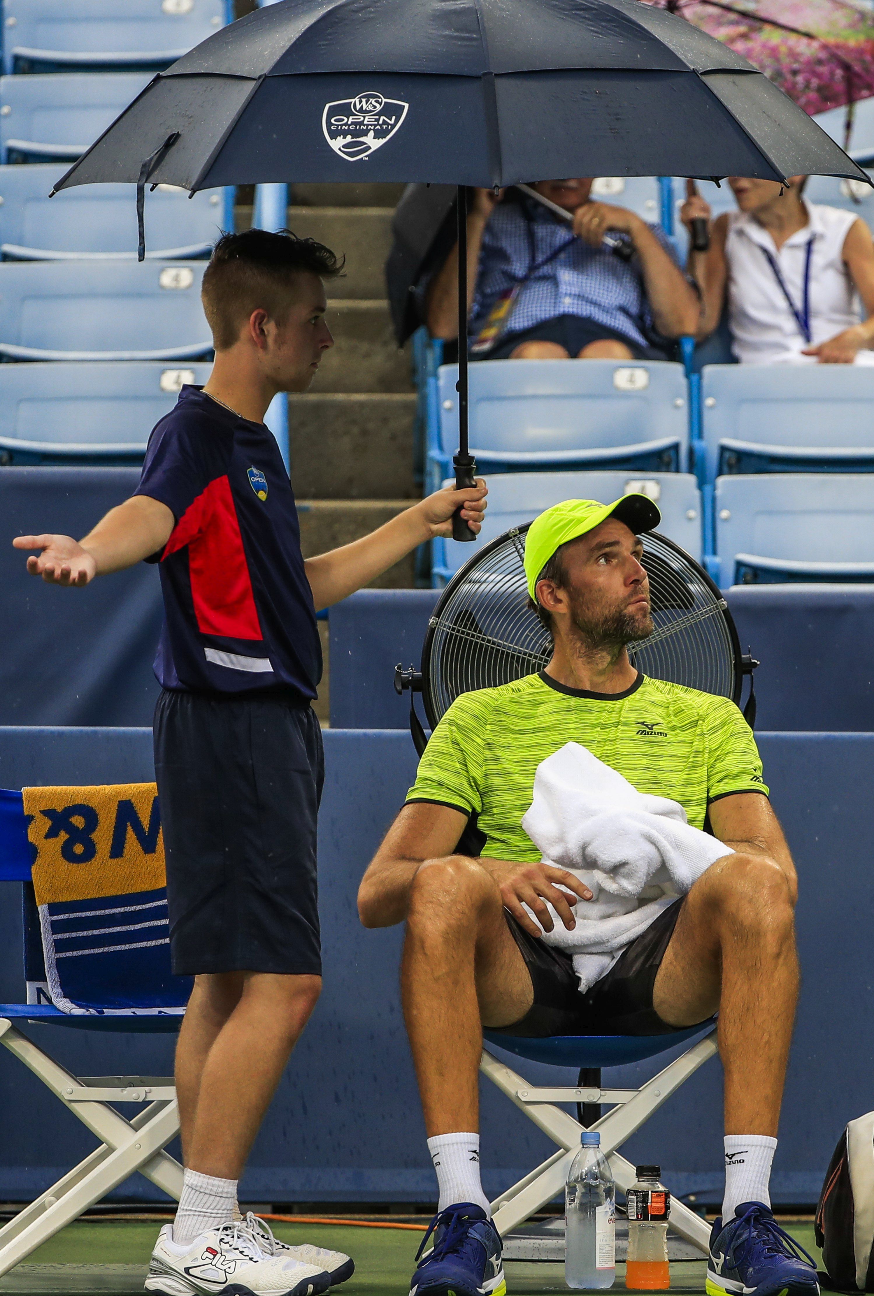 epa06149206 Ivo Karlovic of Croatia sits under an umbrella as rain starts to fall during his match against Nick Kyrgios of Australia at the Western & Southern Open tennis tournament at the Linder Family Tennis Center in Mason, Ohio, USA, 17 August 2017.  EPA/TANNEN MAURY