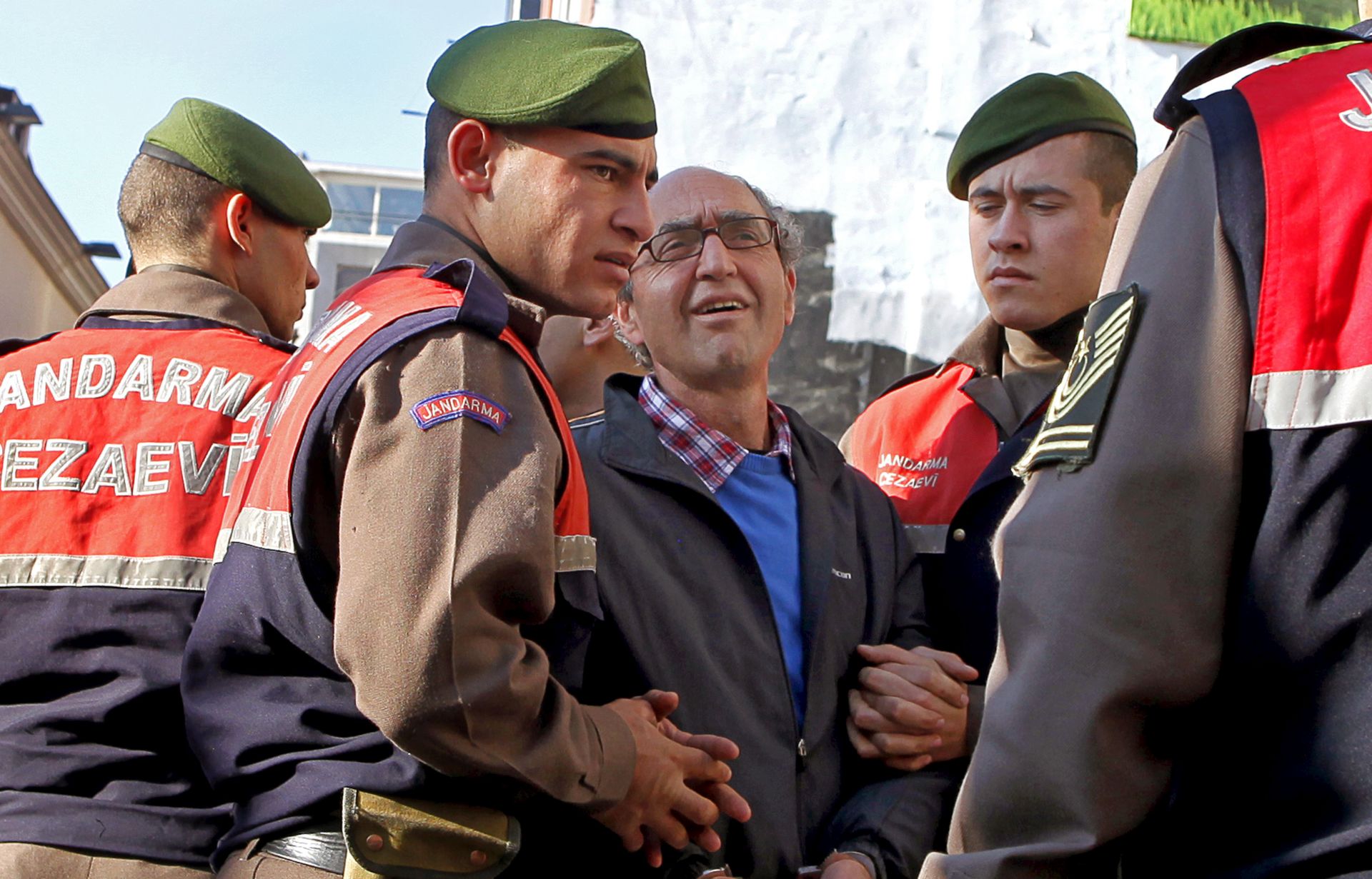 epa06151296 (FILE) - Turkish-born German publisher Dogan Akhanli (C with glasses) wears handcuffs as he is escorted to the court building prior to his trial at the Besiktas court in Istanbul, Turkey, 08 December 2010 (reissued 19 August 2017). According to reports, German writer Dogan Akhanli was arrested on early 19 August 2017 during his vacation in Granada, Spain. His arrest came under the request of Turkish authorities who had Interpol issue a 'red notice' for the German citizen of Turkish decent.  EPA/TOLGA BOZOGLU