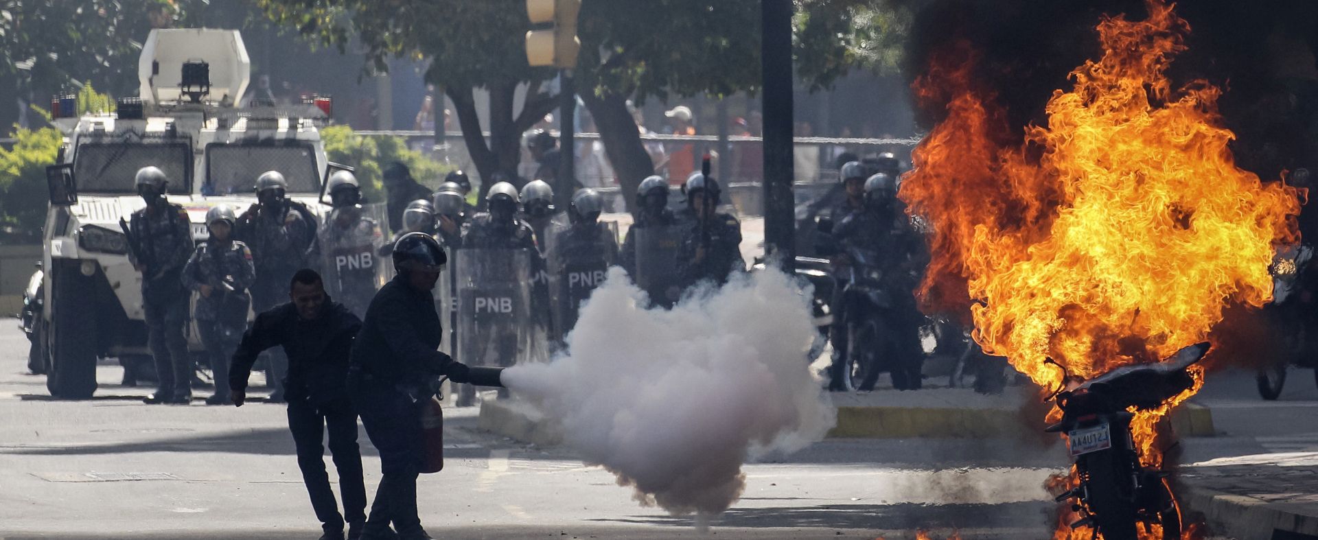 epa06125221 Police try to extinguish a burning motorcycle burns as opposition demonstrators protest the National Constituent Assembly in Caracas, Venezuela, 04 August 2017. Venezuela is installing the 500 member assembly denounced by opposition groups and international leaders and which will rewrite the constitution.  EPA/Miguel Gutierrez