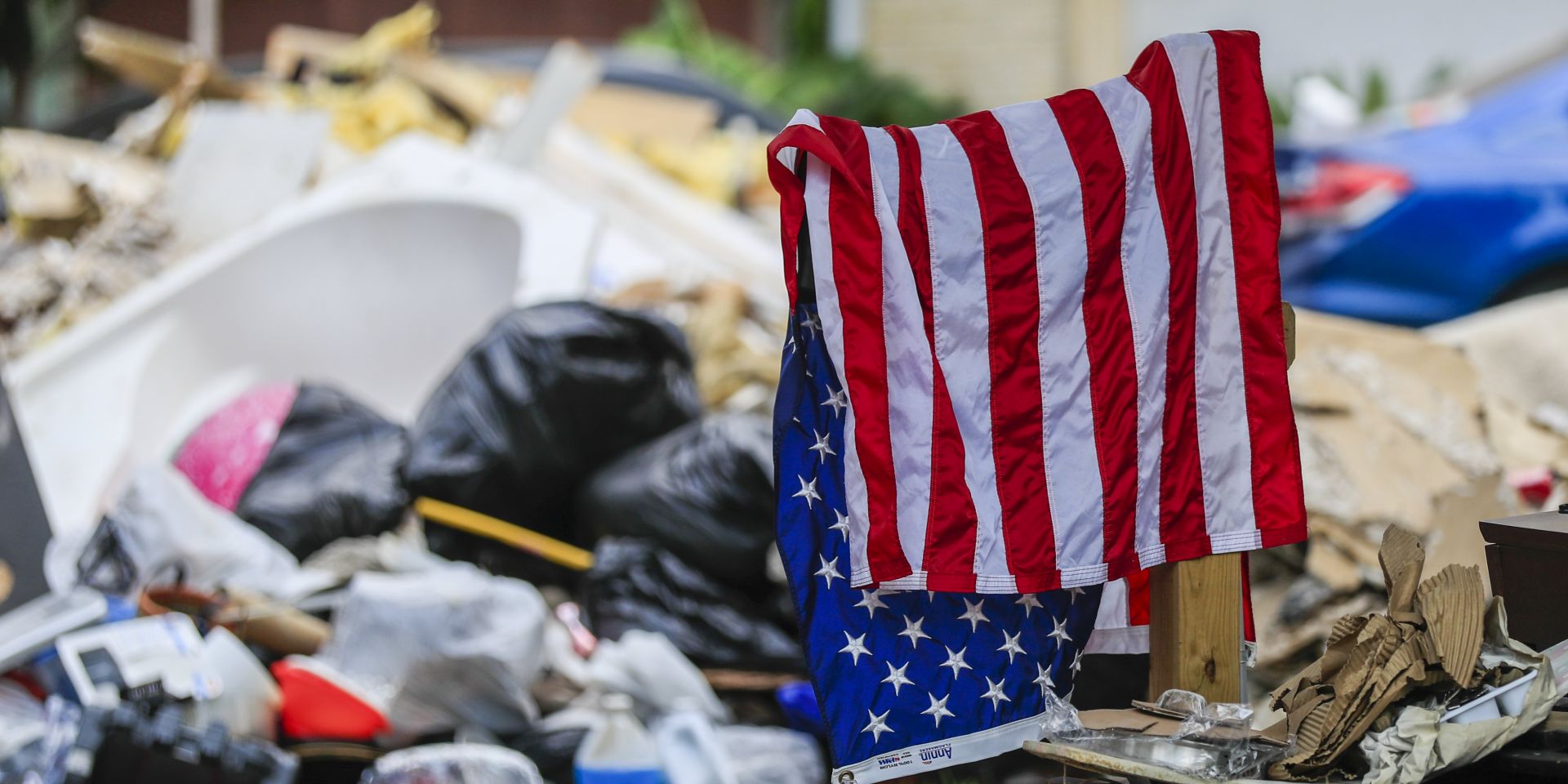 epa06182111 A US Flag hangs drying near debris removed from homes that were flooded by rains from Hurricane Harvey in the Hunterwoods Village neighborhood of Houston, Texas, USA, 03 September 2017. Hurricane Harvey made landfall on the south coast of Texas as a major hurricane category 4. The last time a major hurricane of this size hit the United States was in 2005.  EPA/TANNEN MAURY