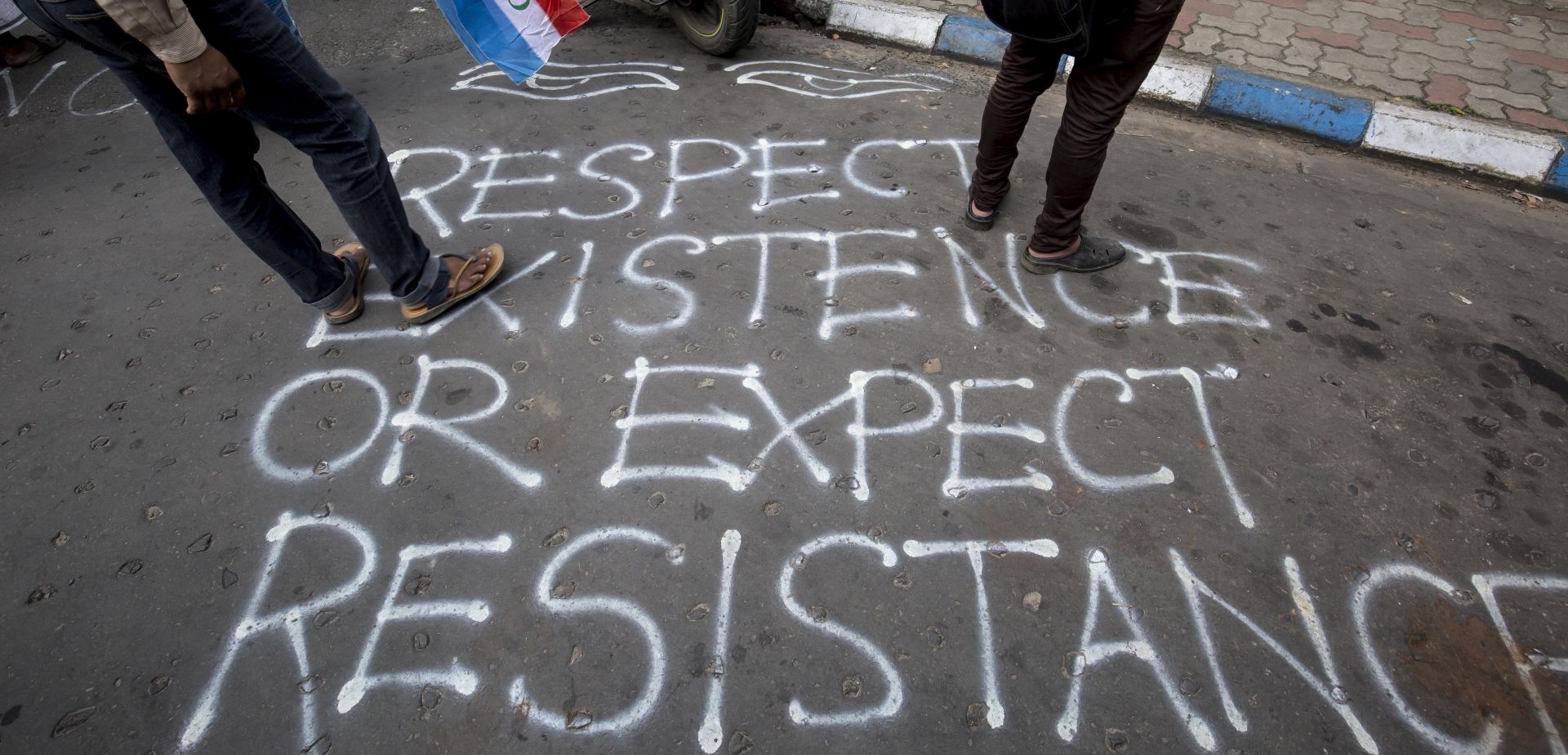epa06189795 People walk on a slogan written on the street during a protest near the Myanmar embassy in Calcutta, Eastern India, 07 September 2017. The Protest was held against the Myanmar government after thousands of Muslims in Myanmar crossed to Bangladesh following a series of violence that killed nearly 400 people during August 2017, the UN refugee agency said.  EPA/PIYAL ADHIKARY