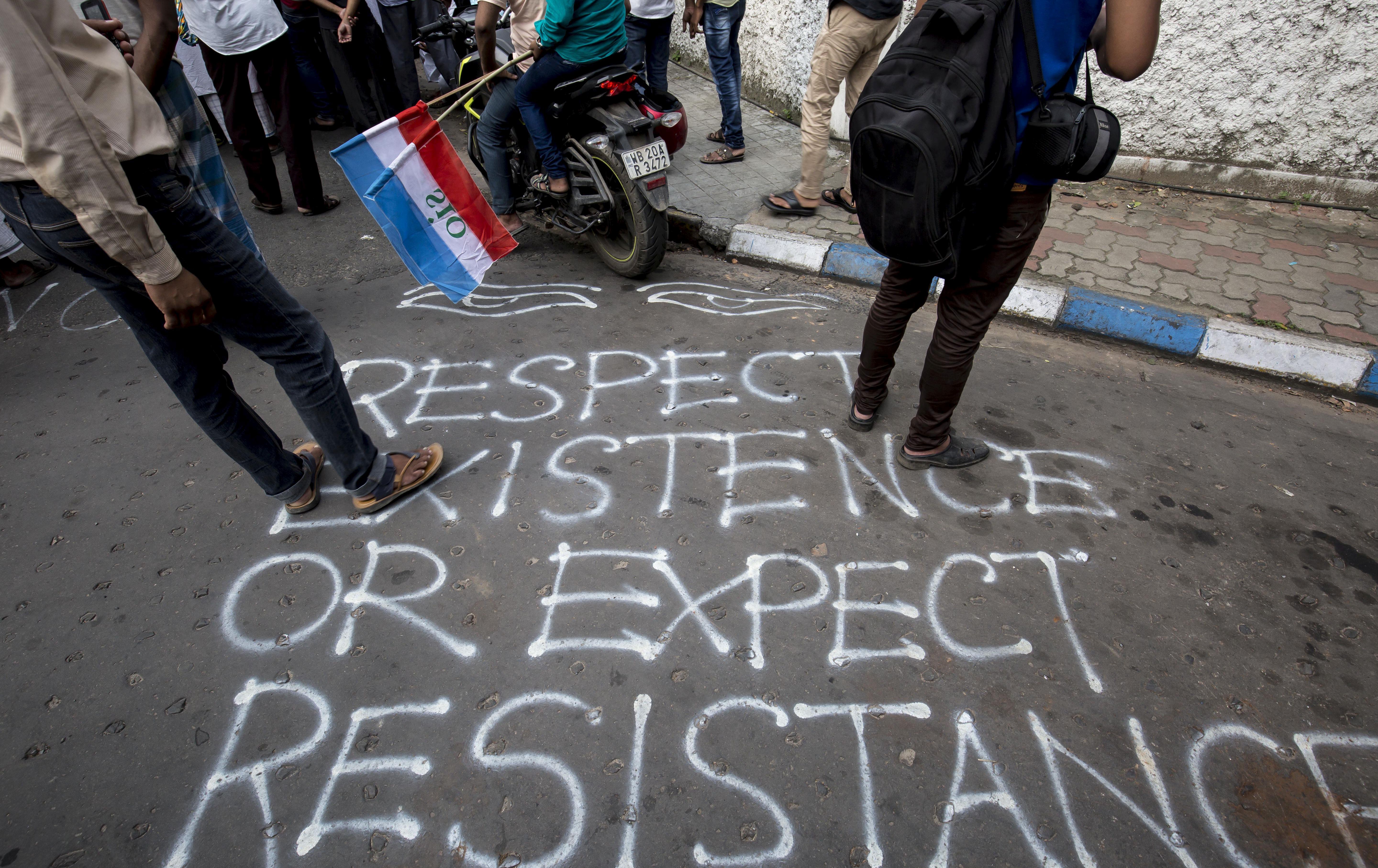 epa06189795 People walk on a slogan written on the street during a protest near the Myanmar embassy in Calcutta, Eastern India, 07 September 2017. The Protest was held against the Myanmar government after thousands of Muslims in Myanmar crossed to Bangladesh following a series of violence that killed nearly 400 people during August 2017, the UN refugee agency said.  EPA/PIYAL ADHIKARY