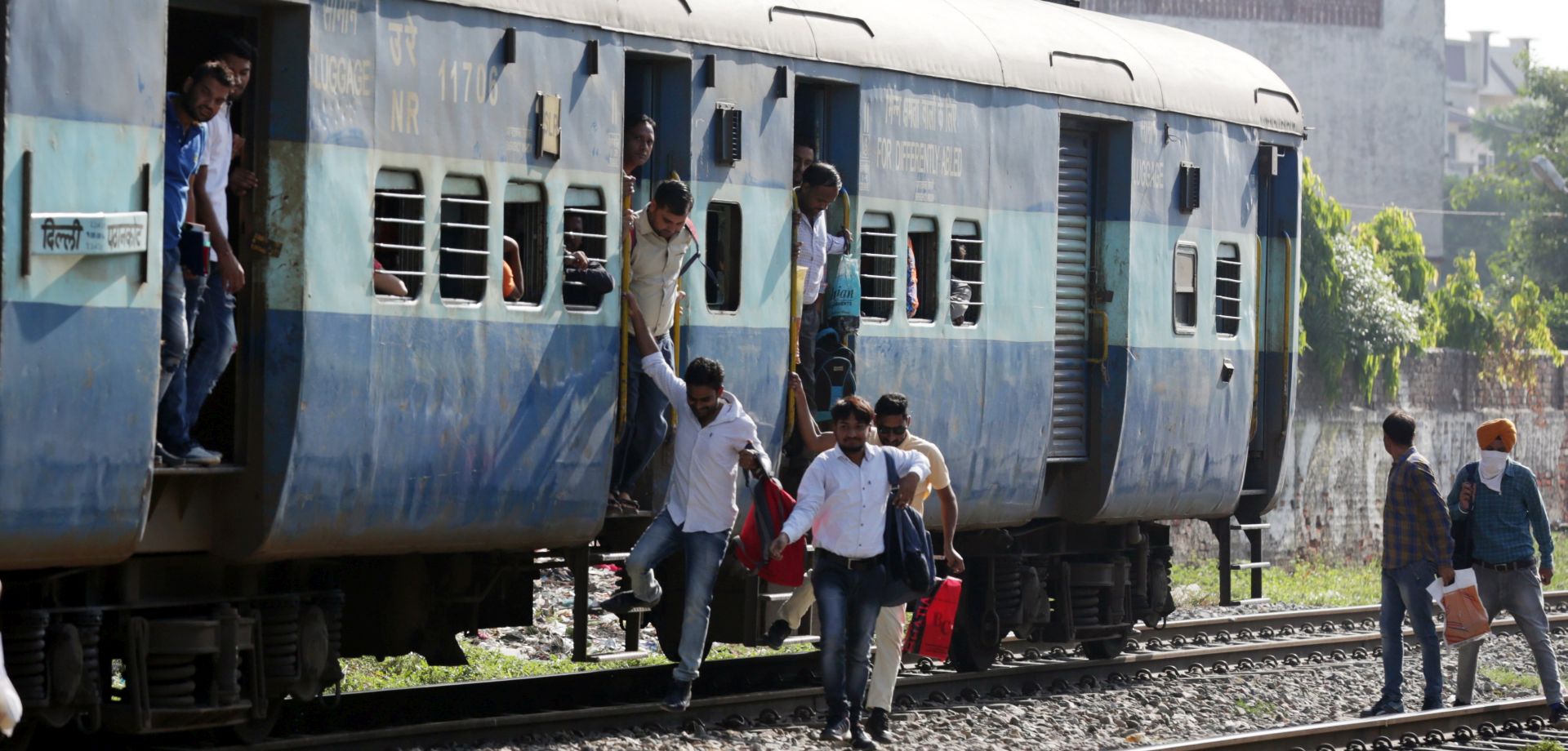 epa06207824 Indian commuters get off a slow moving train near a railway crossing as the train approaches the railway station in Amritsar, India, 16 September 2017. On 14 September, Indian Prime Minister Narendra Modi and his Japanese counterpart Shinzo Abe laid the foundation stone of the $17 billion Ahmedabad-Mumbai high-speed rail project for the Bullet train, in Gujarat state. The Bullet train project has come under attack from the opposition parties with Congress party stating that the launch of the project is timed with upcoming assembly elections in the state of Gujarat. The party said that the government should give priority to the railway safety first, instead of launching Bullet train as 29 major railway accidents have killed 259 passengers and injured 973 since the Modi government assumed office.  EPA/RAMINDER PAL SINGH