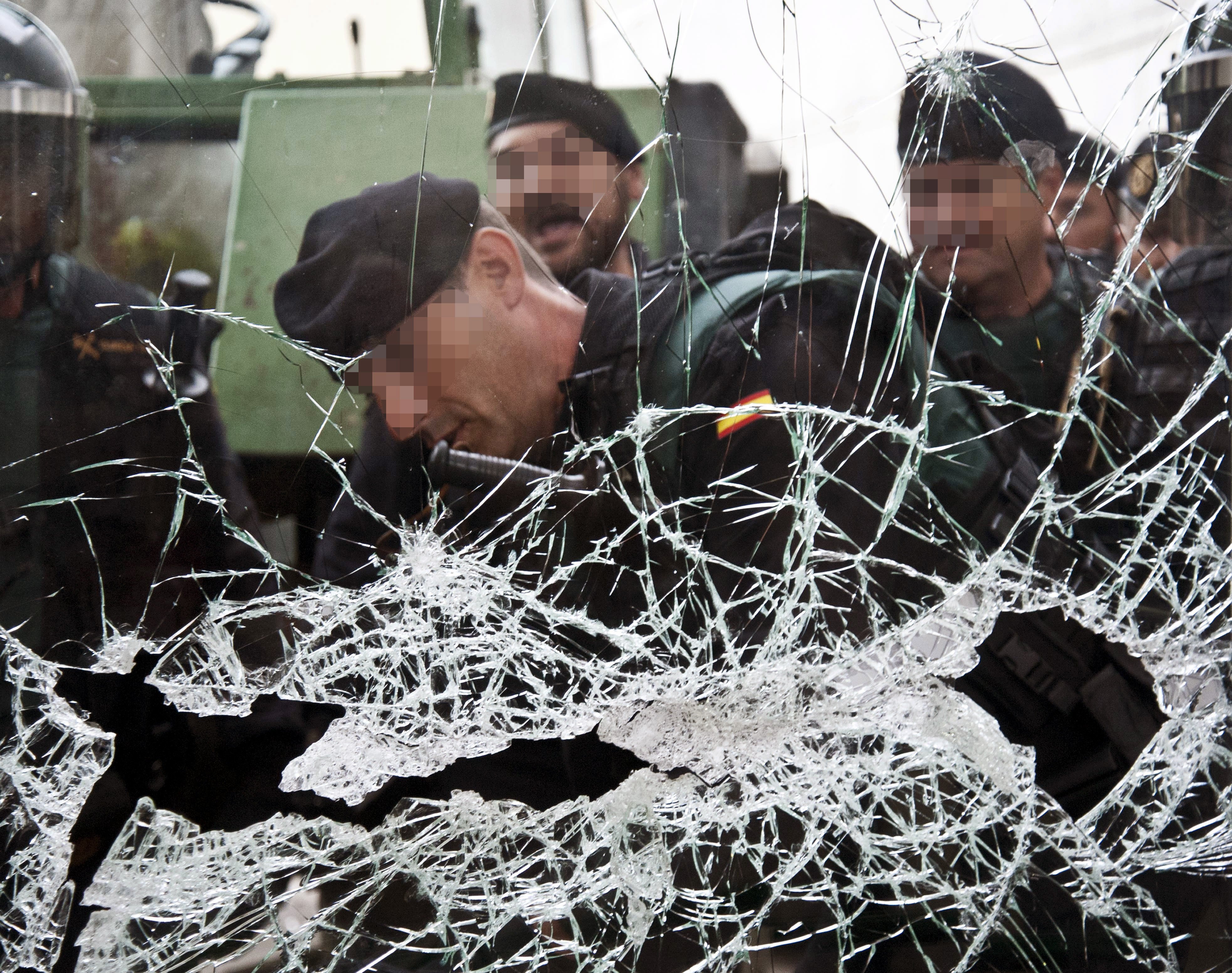 epa06237517 Spanish National policemen are seen behind a broken window during clashes between Catalan pro-independence people and police forces at the Sant Julia de Ramis sports center in Girona, where the Catalan President, Carles Puigdemont was expected to vote, in Girona, Catalonia, northeastern Spain, on 01 October 2017. National Police officers and Civil guards have been deployed in Barcelona to prevent the people from entering to the polling centers and vote in the Catalan independence referendum, that has been banned by the Spanish Constitutional Court. The police action has provocked clashes between pro-independence people and the police forces.  EPA/Andreu Dalmau ATTENTION EDITORS: POLICEMAN'S FACE BLURED DUE TO SPANISH LAW
