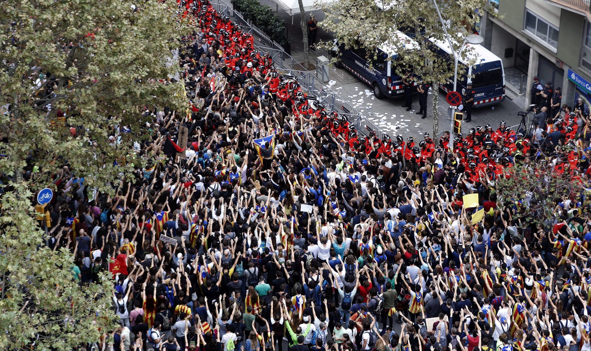 epa06241292 People protest while Catalan policemen (Mossos d'Esquadra) remain on guard at the headquarters of the People's Party (PP) in Barcelona, during protests held on occasion of the general strike called in Catalonia, Spain, 03 October 2017. Unions CGT, IAC, COS and CSC called for a general strike in Catalonia as a protest against the Spanish Government measures to avoid the celebration of the referendum last 01 October 2017. According to unions, the strike is having a big support in sectors such as transport, shops, stowage or agriculture.  EPA/ANDREU DALMAU