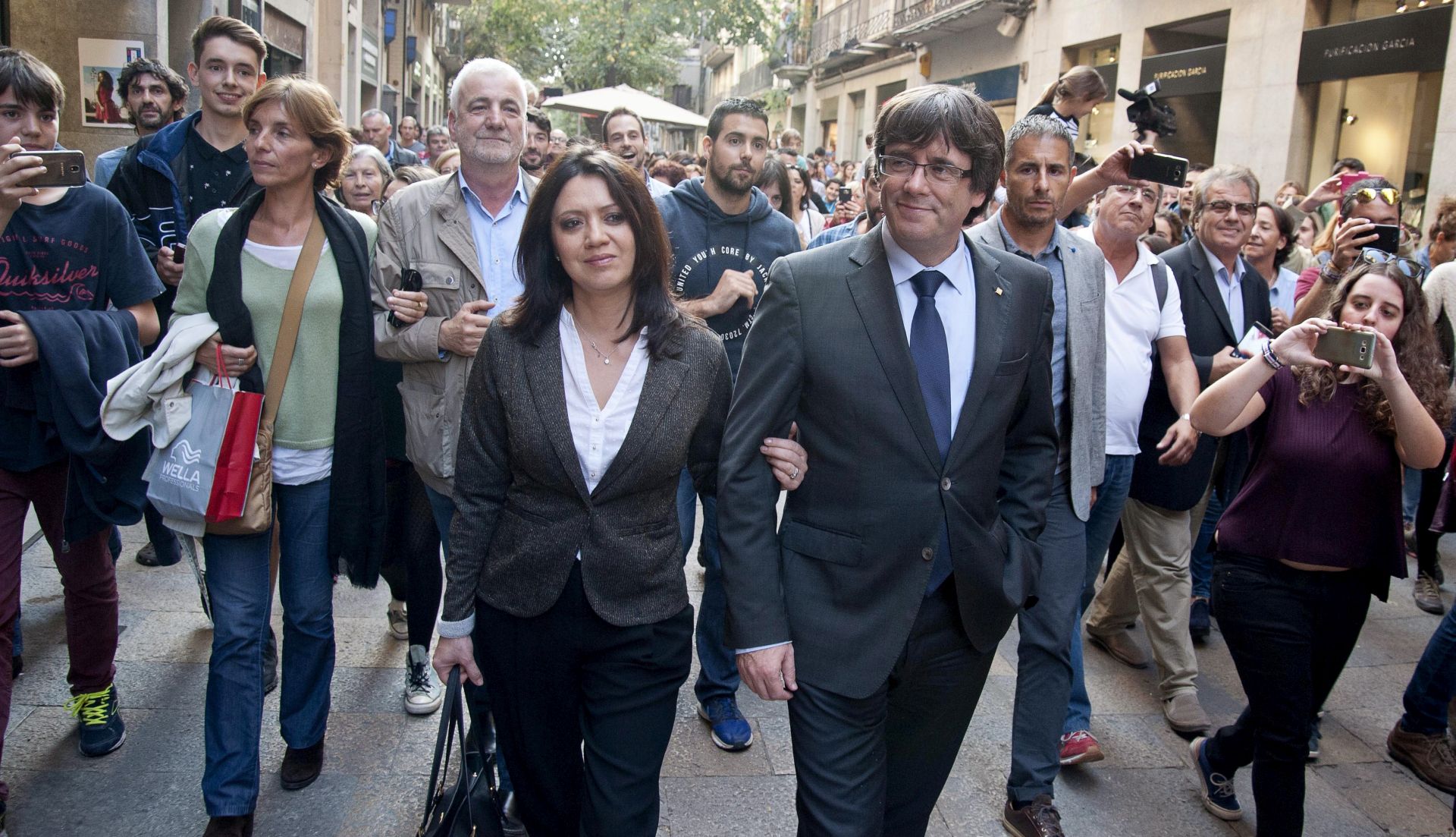 epa06295220 Catalan dismissed President, Carles Puigdemont (CR), and his wife, marcela Topor greets supporters as he leaves a restaurant in Vi square, Girona (Catalonia, northeastern Spain), 28 October 2017. Puigdemont offered a speech earlier today after Spanish Government removed him from post the previous day as part of the package of initiatives applied in observance to the Spanish Constitution's 155 Article. Puigdemont said that he does not acknowledge his dismissal as Catalan President and asked Catalans to have 'patience, persistance and perspective' to 'defend the conquests achieved up to now'.  EPA/Robin Townsend