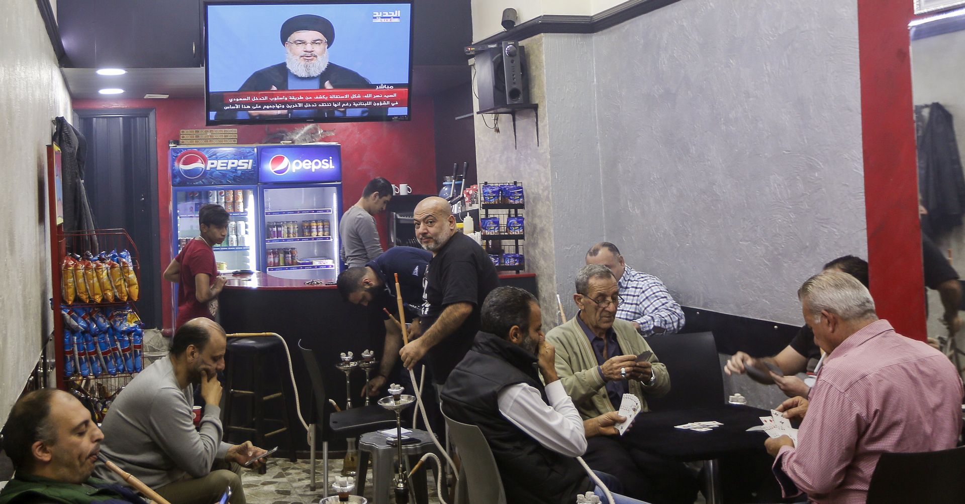 epa06310456 Lebanese men play card and smoke Shisha while listening to the speech of Hezbollah Leader Hassan Nasrallah on TV at a coffee shop in Beirut, Lebanon, 05 November 2017. Lebanese Prime Minister Saad Hariri Announced on 04 Novermber 2017 that he resigns from the Prime Minister's office. According to media reports, Hariri said that the current political climate reminds him with the time before the assassination of his father, former Lebanese Prime Minister Rafic Hariri, and he also mentioned Iran's influence in his country, and the region. Hariri came into office for his second term on 18 December 2017. Nasrallah said in a televised speech that the resignation of Saad Hariri is a decision that came from Saudi Arabia, and that its reasons are not clear to anyone in Lebanon. And he asked his supporters and all the Lebanese parties and All political currents in the country to remain calm and maintain civil peace, and added that Saudi Arabia is interfering in the affairs of Lebanon and is working to undermine its civil peace.  EPA/NABIL MOUNZER