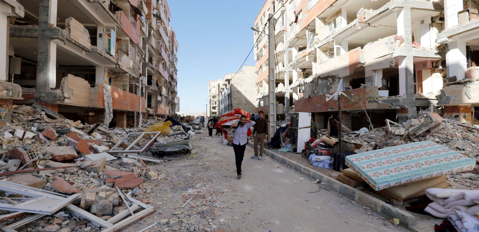 epa06328031 An Iranian man carries belongings from collapsed buildings at the earthquake site in the city of Sare Pole-Zahab in Kermanshah Province, Iran, 14 November 2017. A powerful 7.2 magnitude earthquake that struck Iran's Kermanshah province bordering Iraq late 12 November 2017 has at least killed over 440 inhabitants and left at least another 3,950 injured, Iranian authorities said.  EPA/ABEDIN TAHERKENAREH