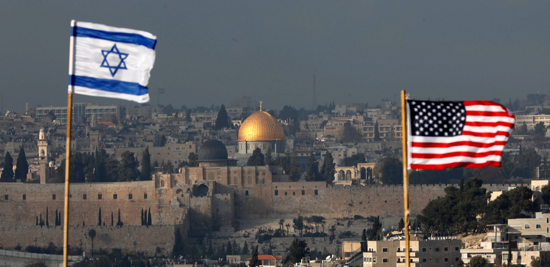 epa06387474 Israeli and US flags fly against the backdrop of the Old City of Jerusalem and the Dome of the Rock on the roof of a building in the Jewish neighborhood and Settlement of Nof Zion located inside the Palestinian neighborhood of Jabal Mukaber in East Jerusalem, 13 December 2017. US President Trump on 06 December announced he is recognizing Jerusalem as the capital of Israel and ordered that the US embassy be moved there from Tel Aviv, an announcement that has been met with widespread international criticism and led to increased tension in the region.  EPA/ABIR SULTAN