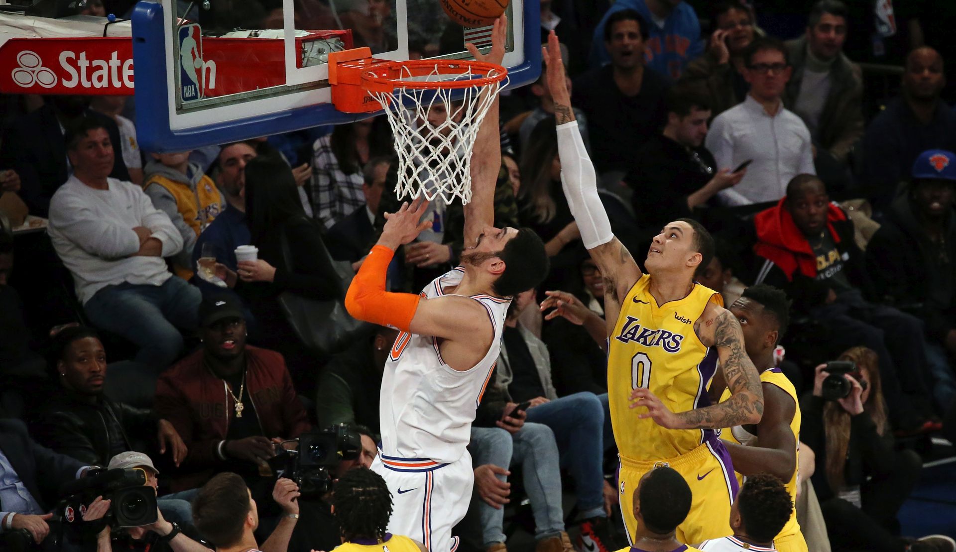 epa06386160 New York Knicks center Enes Kantor (C) of Turkey scores over Los Angeles Lakers forward Kyle Kuzma (R) during the second half of the NBA basketball game between the Los Angeles Lakers and the New York Knicks at Madison Square Garden in New York, New York, USA, 12 December 2017.  EPA/PETER FOLEY