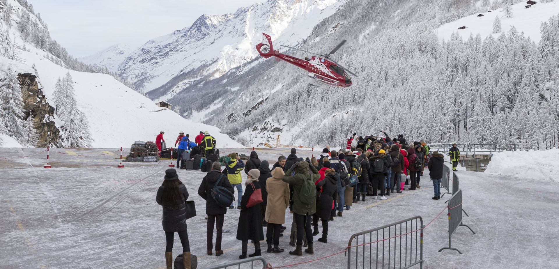 epa06428456 Tourists wait in line at the heliport of Air Zermatt for a flight by airlift into the valley to Raron, in Zermatt, Switzerland, 10 January 2018. Due to heavy snowfall and rain showers, Zermatt can only be reached by air. Swiss authorities have closed roads and train service into the town of Zermatt amid a heightened risk of avalanches, stranding some 13,000 tourists in the town.  EPA/DOMINIC STEINMANN