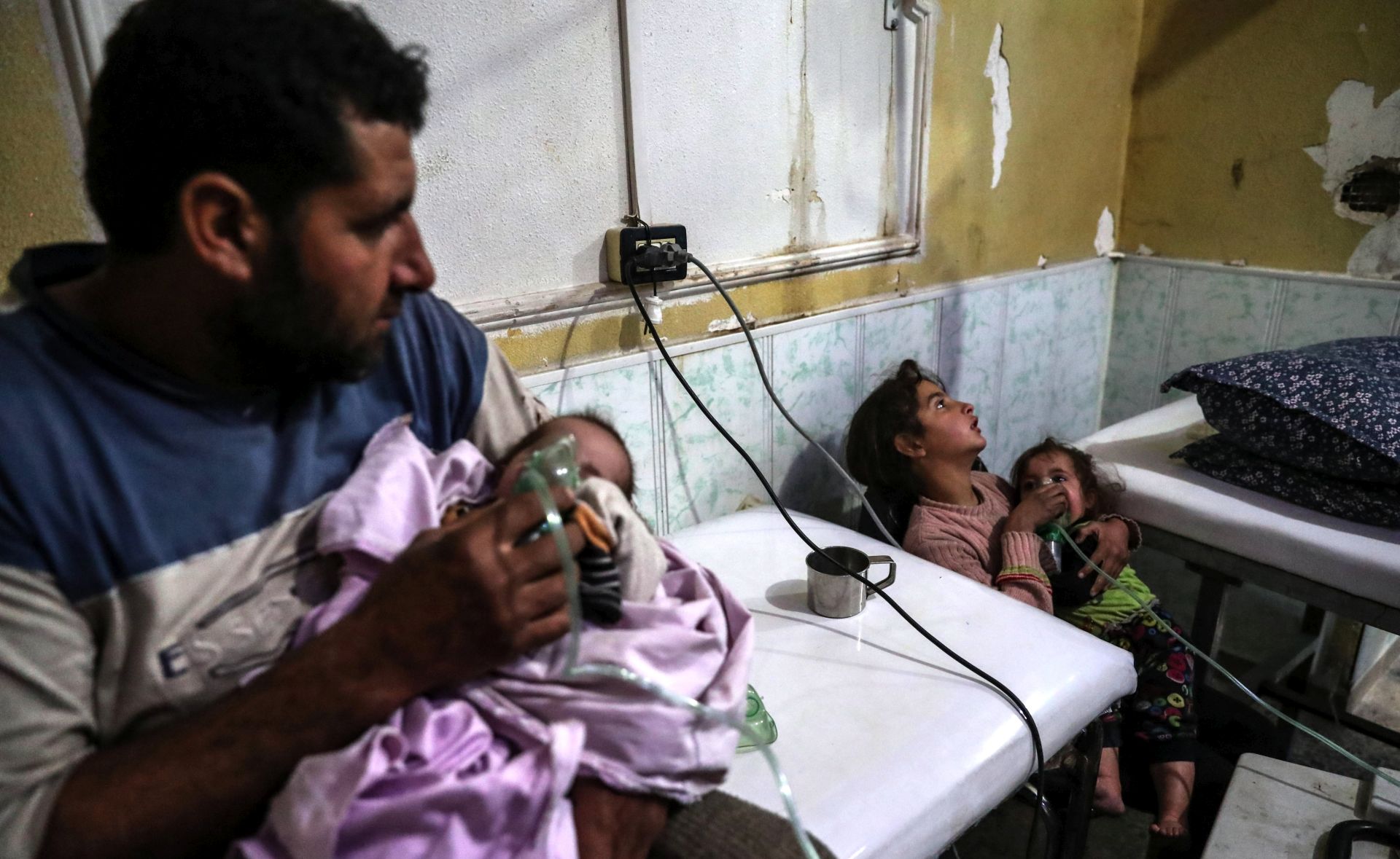 epa06463851 An affected man puts the aerosol mask on his child while his other daughter gives treatment to her other sister, after a shelling attack on rebels-held Eastern al-Ghouta, Syria, 22 January 2018. According to witnesses and activists and local medical sources, allegedly chlorine gas was used during the shelling allegedly by forces loyal to the Syrian government. The smell after the shelling and the symptoms shown on more than 21 people who came for treatments were those shown after the use of chlorine gas. No official confirmation as of yet.  EPA/MOHAMMED BADRA