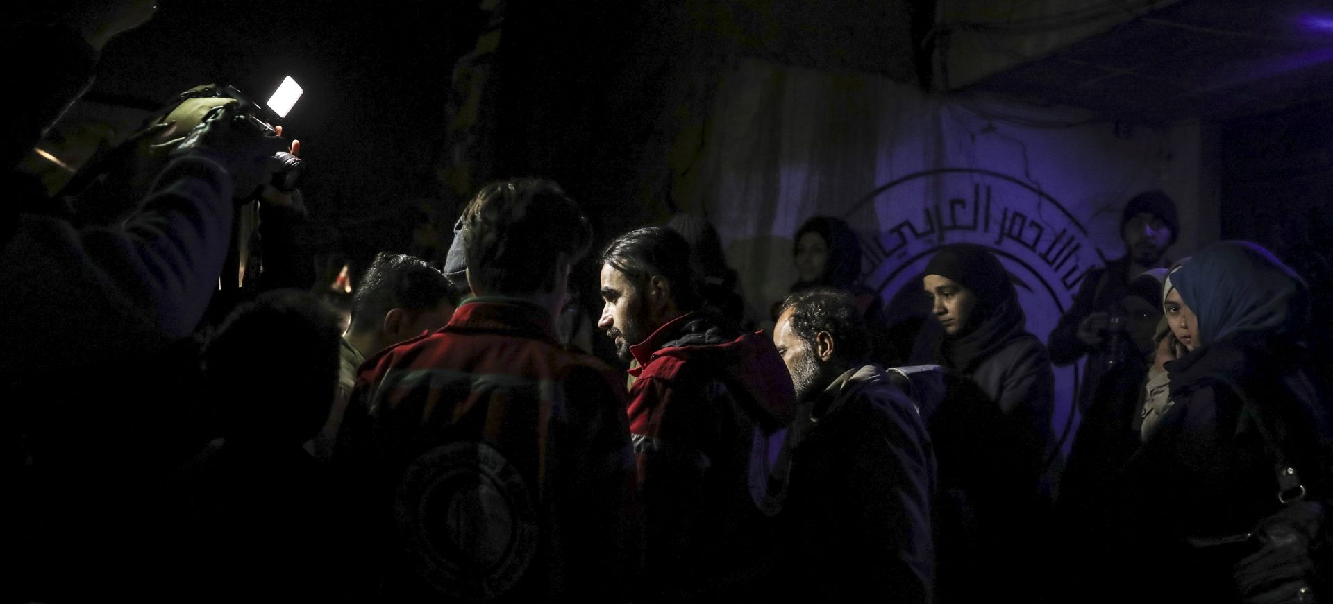 epa06407584 SARC volunteers (in red) stand next to some of the people to be released as part of an exchange agreement during medical evacuations from eastern Ghouta to Damascus, Syria, 27 December 2017. The Syrian Arab Red Crescent (SARC) in association with the International Committee of the Red Cross (ICRC) started the evacuation of 29 critically ill patients from rebel-held eastern Ghouta to Damascus. Jaysh al-Islam, the military ruler of eastern Ghouta, and the Syrian regime, reached a deal allowing 29 people to get medical care in the Syrian capital in exchange of the release of 29 prisoners of the regime captured by the rebels.  EPA/MOHAMMED BADRA