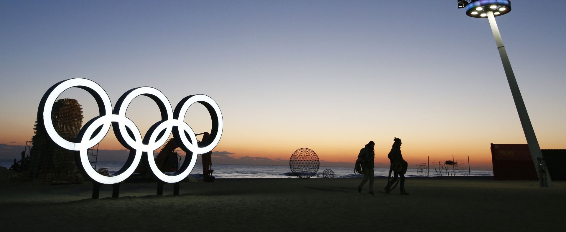 epa06484618 Tourists walk before the sunrise next the Olympic rings installation at Gyeongpo beach, near the venues of Gangneung Ice Arena, Oval and Hockey Centre of the PyeongChang Winter Olympic Games 2018, in Gangneung, South Korea, 30 January 2018. The PyeongChang 2018 Winter Games Olympics, will run from 09 to 25 February 2018.  EPA/JEON HEON-KYUN